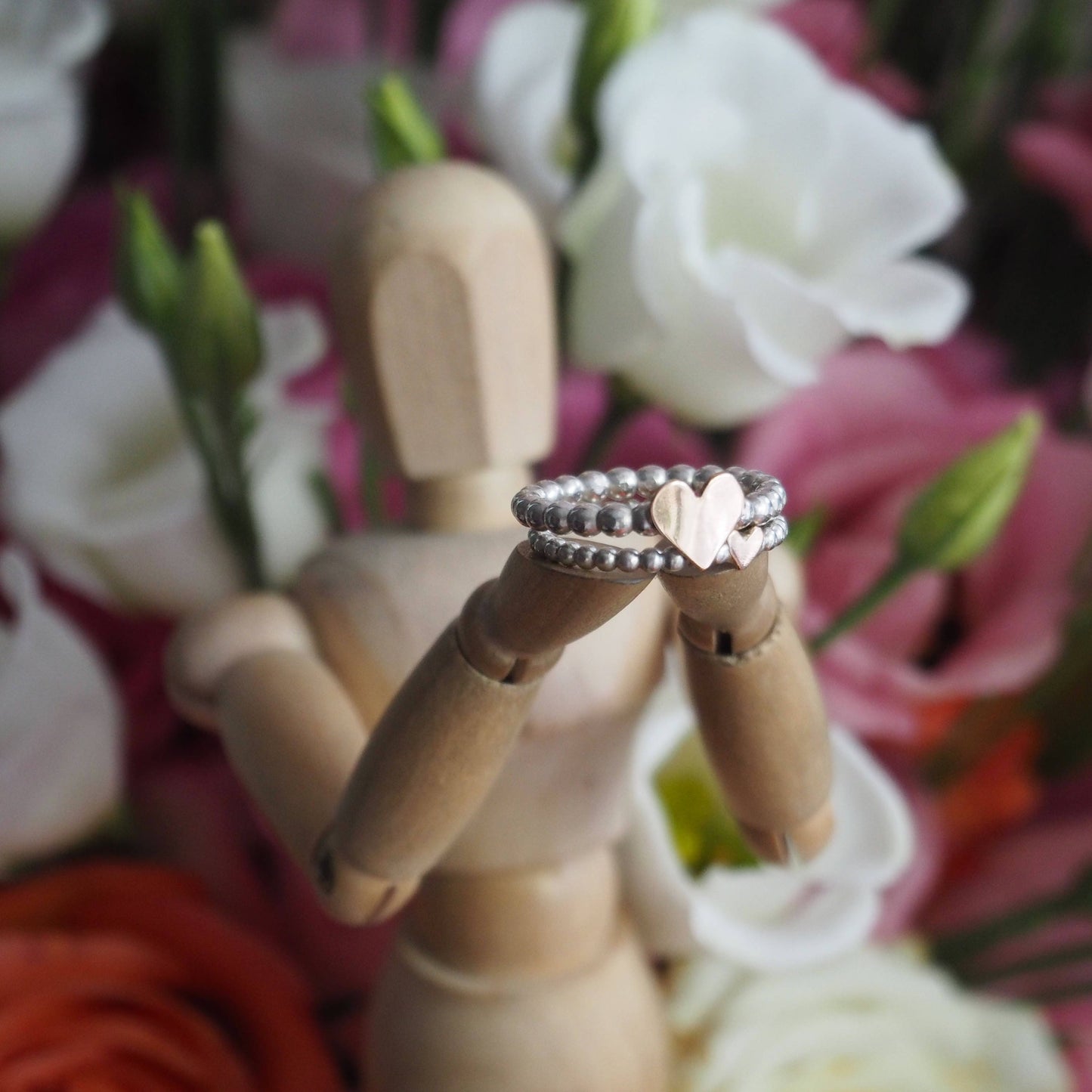 A cute dainty sterling silver and handcut 9ct rose gold heart stacking midi ring on a band of little silver spheres.