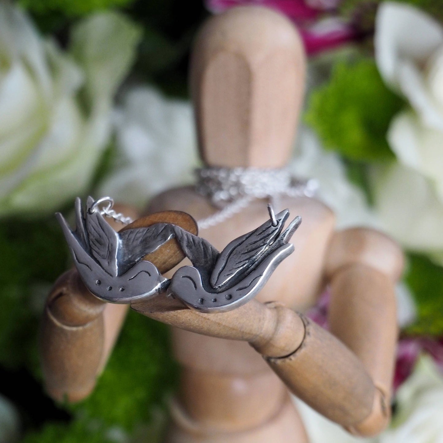 A gorgeous tattoo inspired hand made fine silver love birds necklace hung on a sterling silver chain.