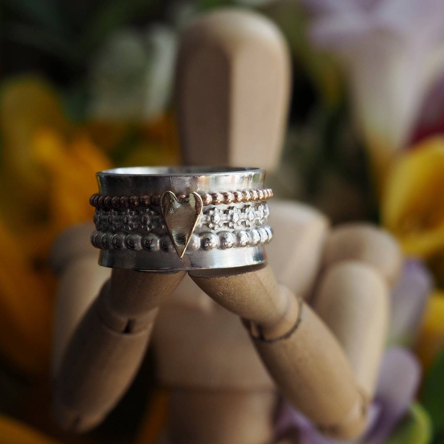 A pretty handmade sterling silver ring with separate handcut 9ct gold heart on flower band, silver and gold filled spinner ring.