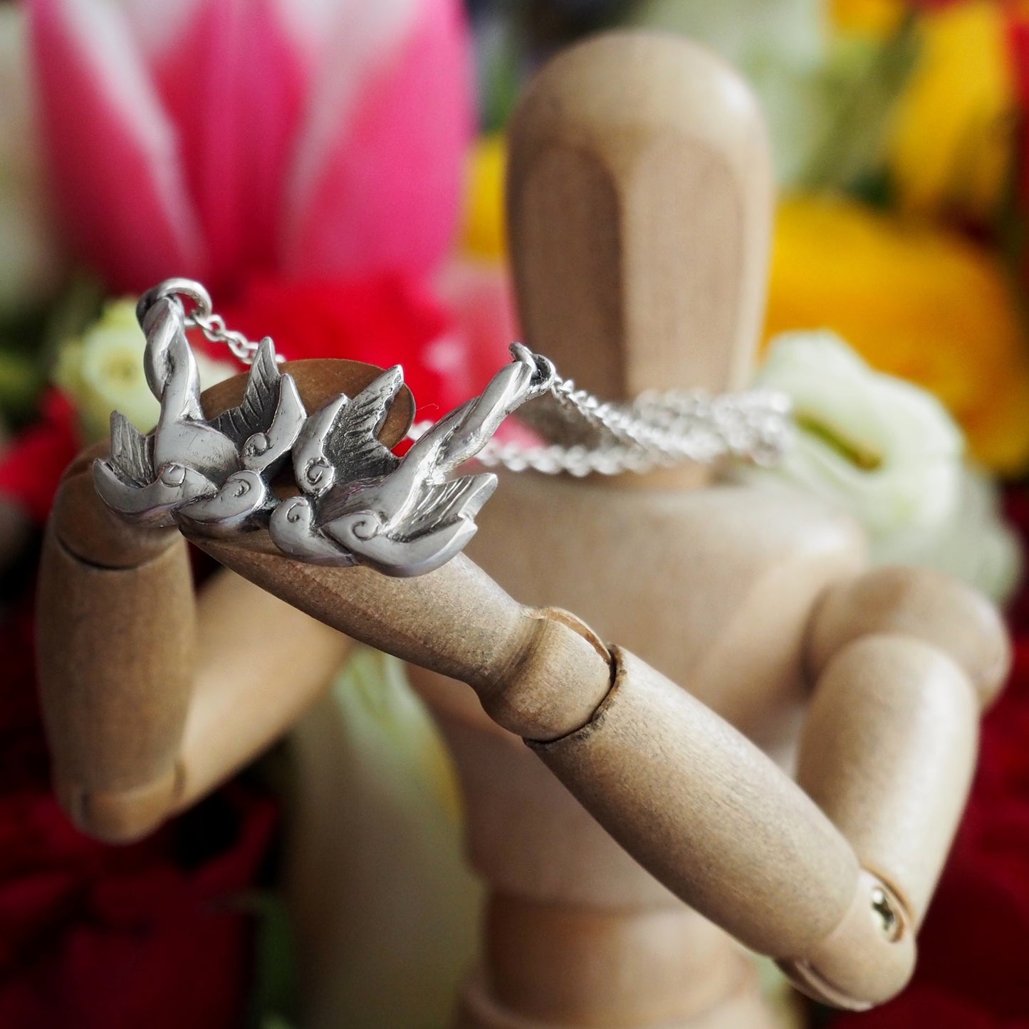 A gorgeous handmade fine silver tattoo inspired love birds necklace hung on a sterling silver chain.