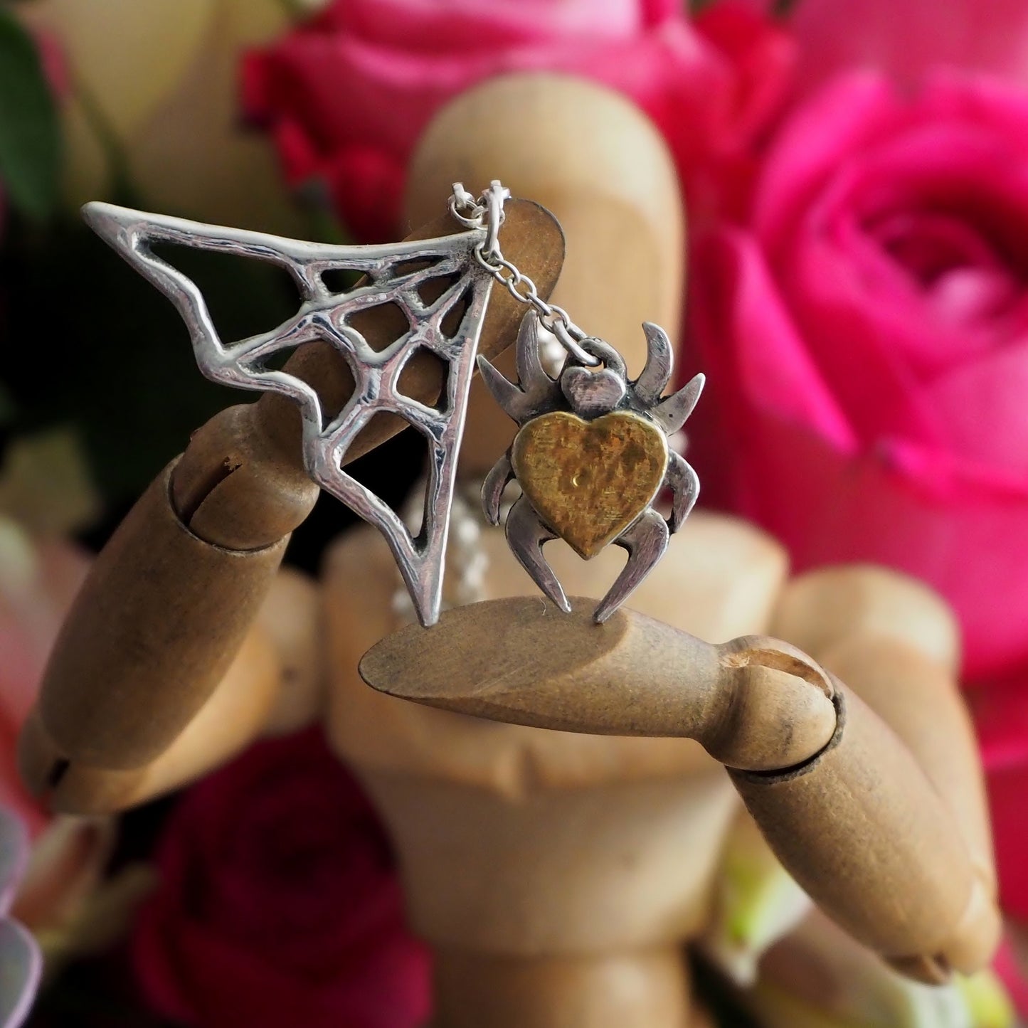 A beautiful handmade, unique fine silver spider necklace with a gold heart body hanging in his web.