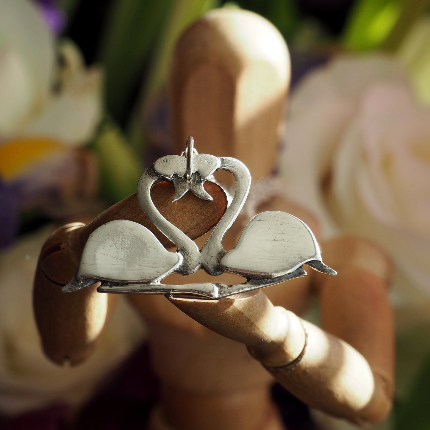 A pair of beautifully simple sitting fine silver flamingos pendant, handmade and hung on a sterling silver chain.