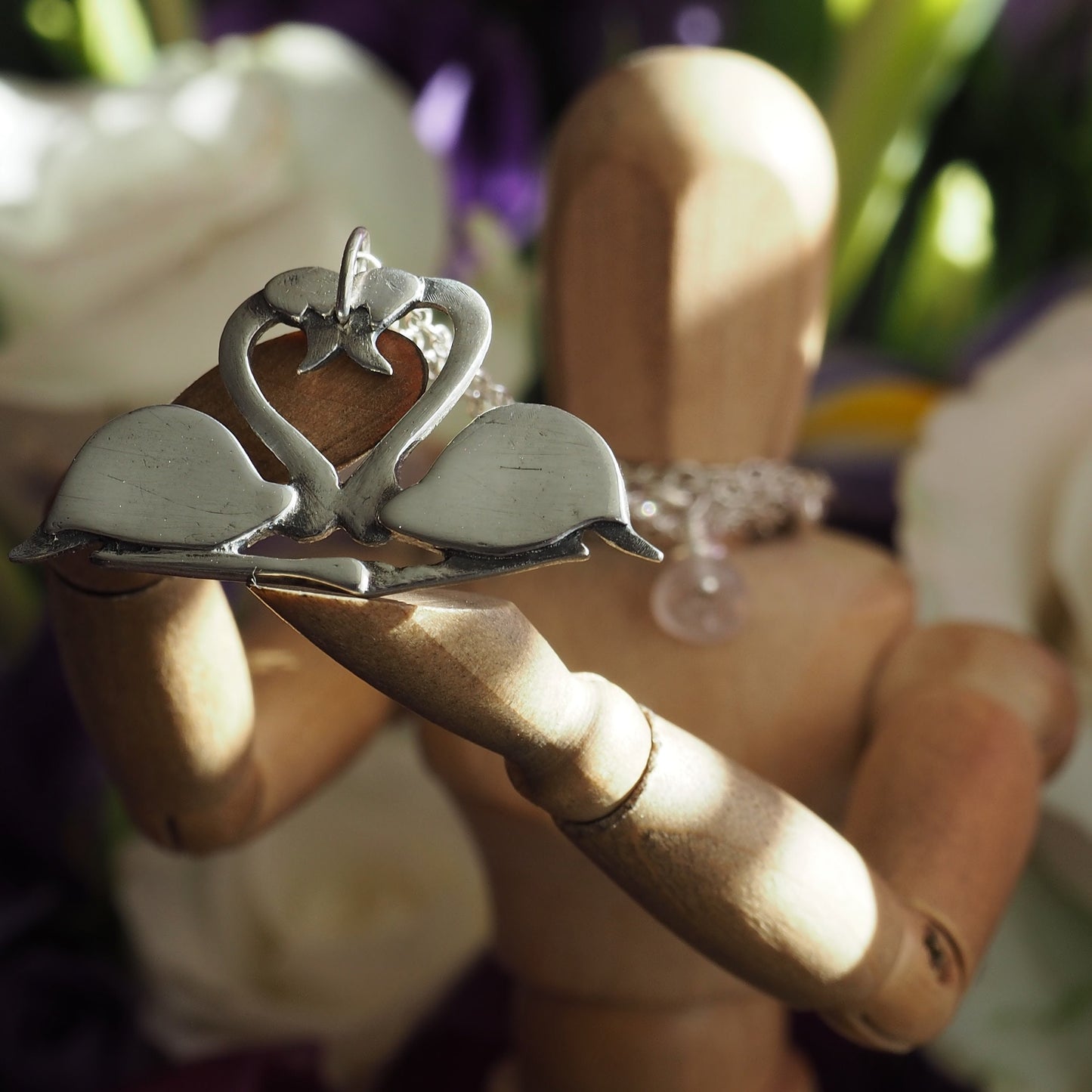 A pair of beautifully simple sitting fine silver flamingos pendant, handmade and hung on a sterling silver chain.