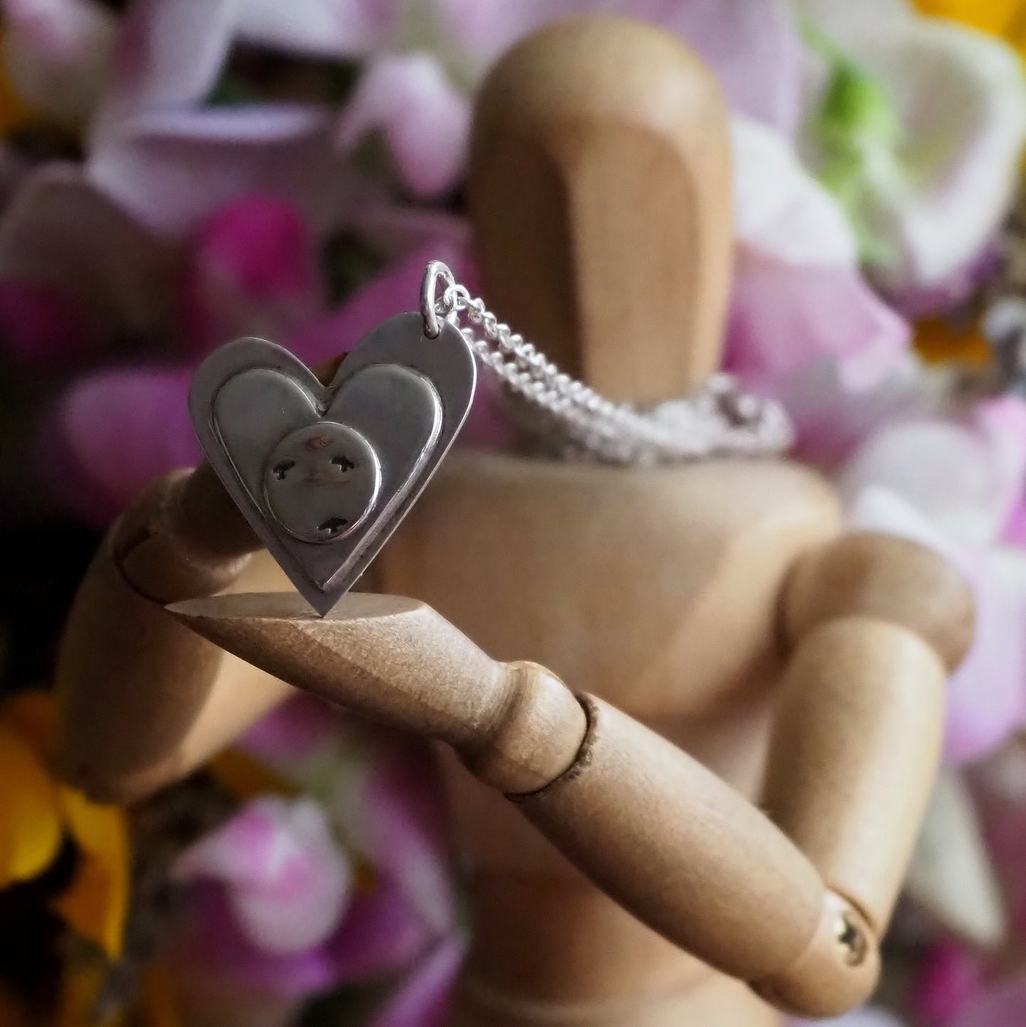 A stunning sterling silver heart pendant layered with another heart and a disc showing a flock of seagulls, hung on a sterling silver chain.