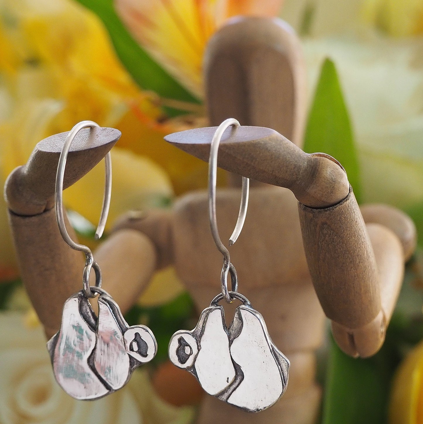 a pair of adorable sleepy sloth earrings handmade in fine 999 silver hung on handmade 925 sterling silver wires.