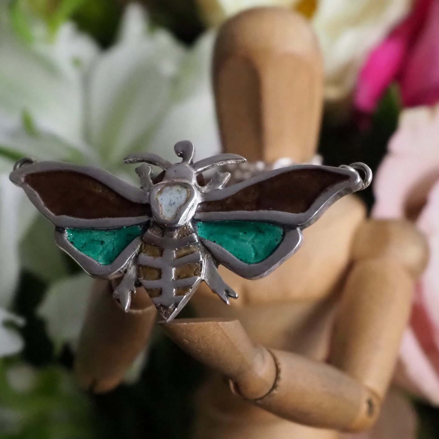 A gorgeous moth pendant, handmade in fine silver and hand enamelled with a skull motif, hung on a sterling silver chain.