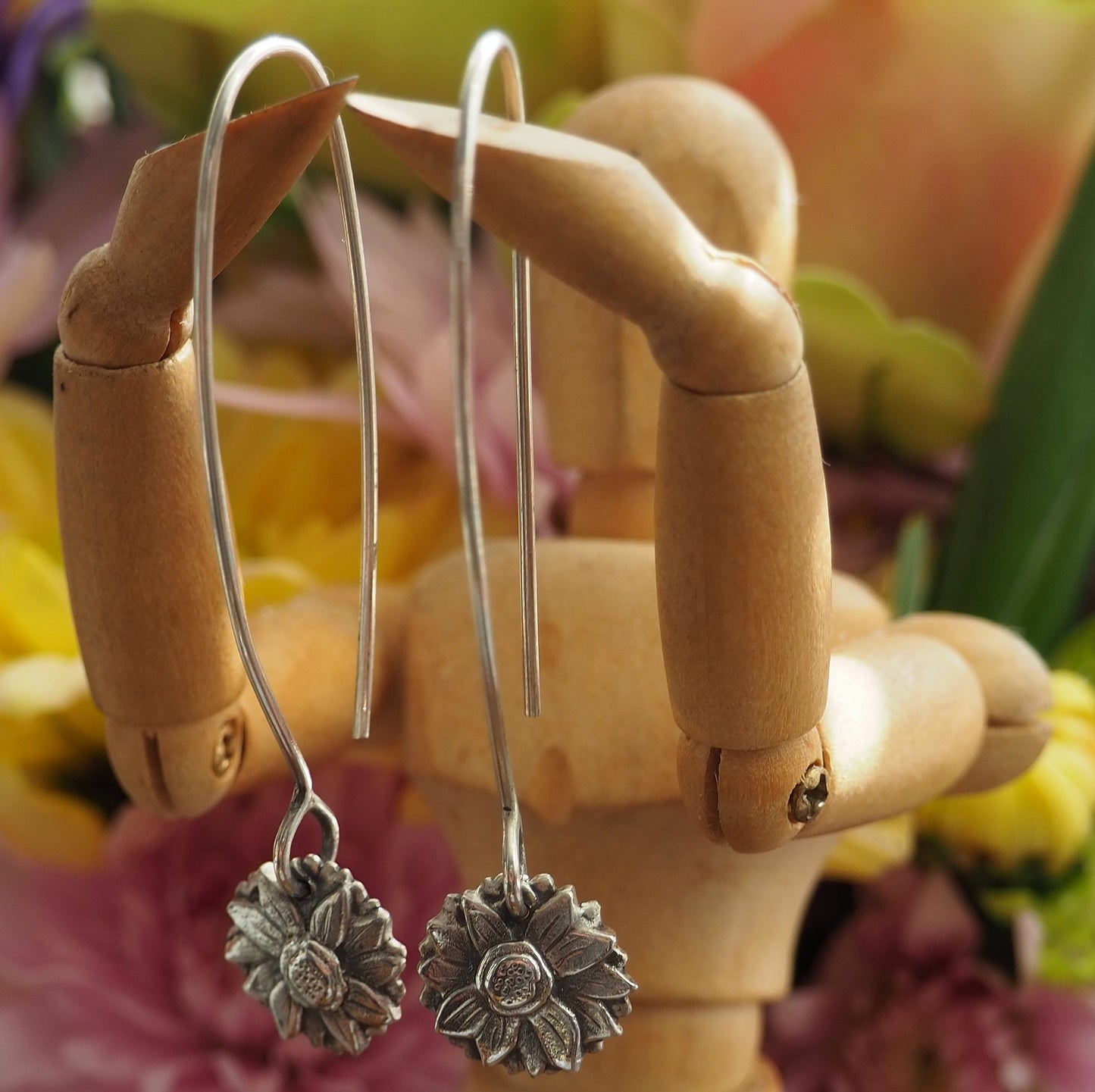 A beautiful pair of sunflower earrings handmade in fine silver and hung on long sterling silver wires.