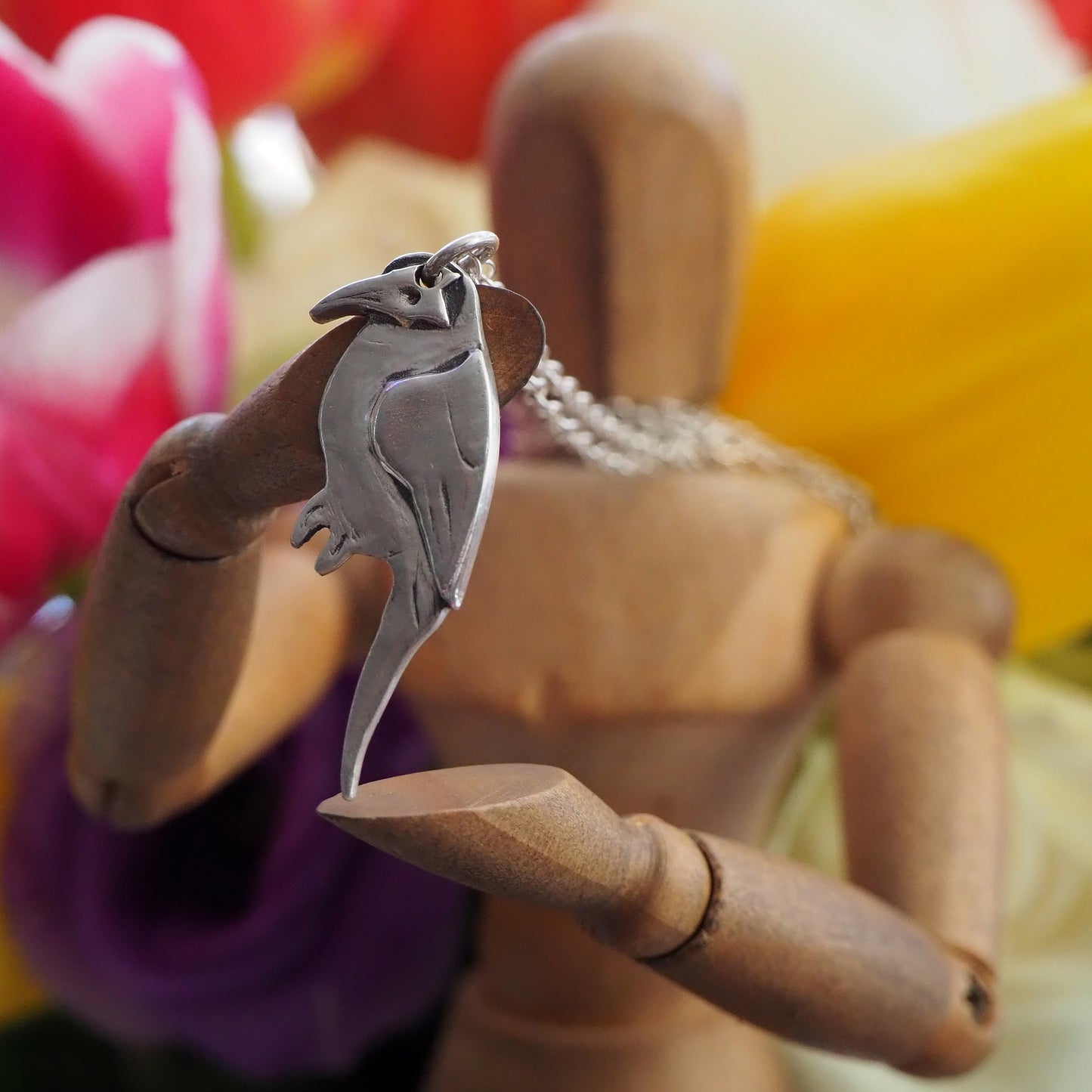 A lovely mynah bird pendant handmade in fine silver hung on a sterling silver chain .