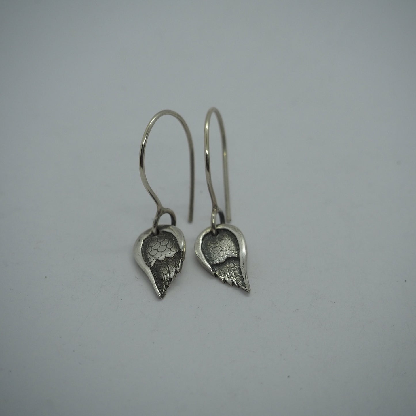 A gorgeous little pair of fine silver angel wing earrings hung on handmade sterling silver loops.