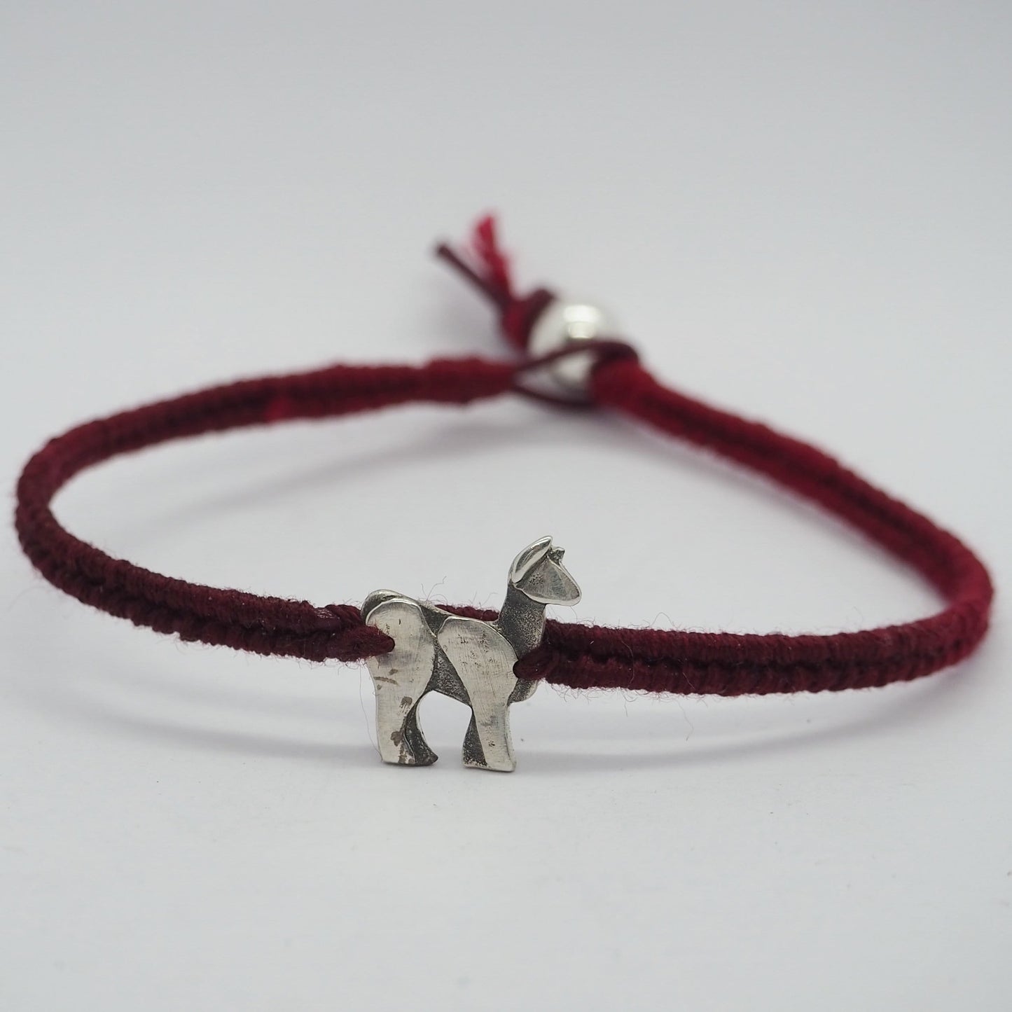 A gorgeous deep red leather, cotton and sterling silver friendship bracelet with a lovely tiny unique handmade fine silver llama