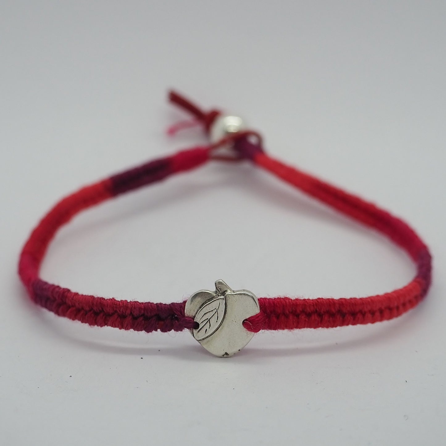 A gorgeous deep red leather and cotton friendship bracelet with a lovely tiny handmade fine silver apple.