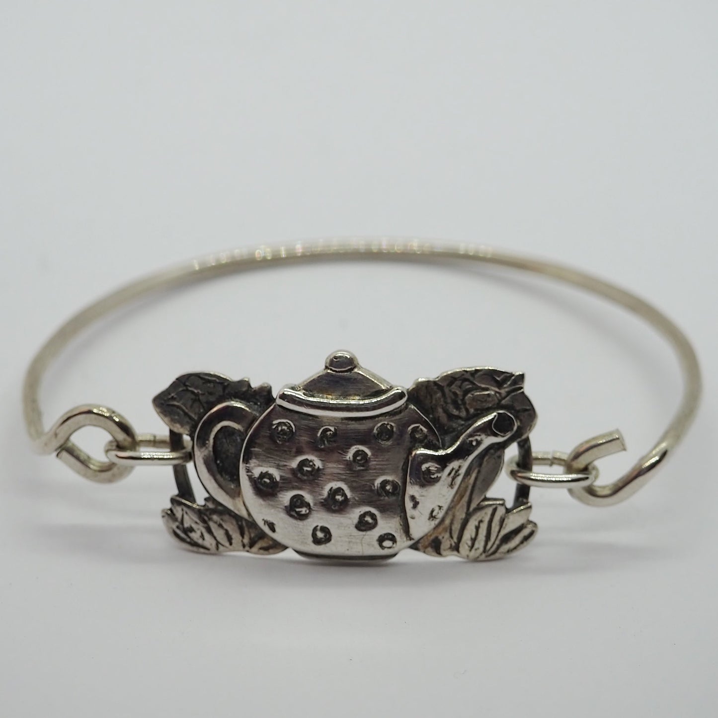 An adorable spotty tea pot and tea roses in handmade in fine silver on a hand beaten sterling silver bangle.