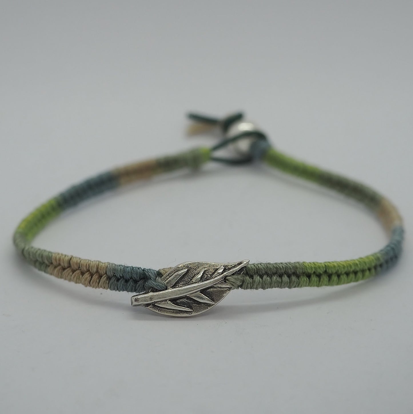 A gorgeous shades of green friendship bracelet in leather, sterling silver and cotton with a gorgeous simple fine silver leaf.