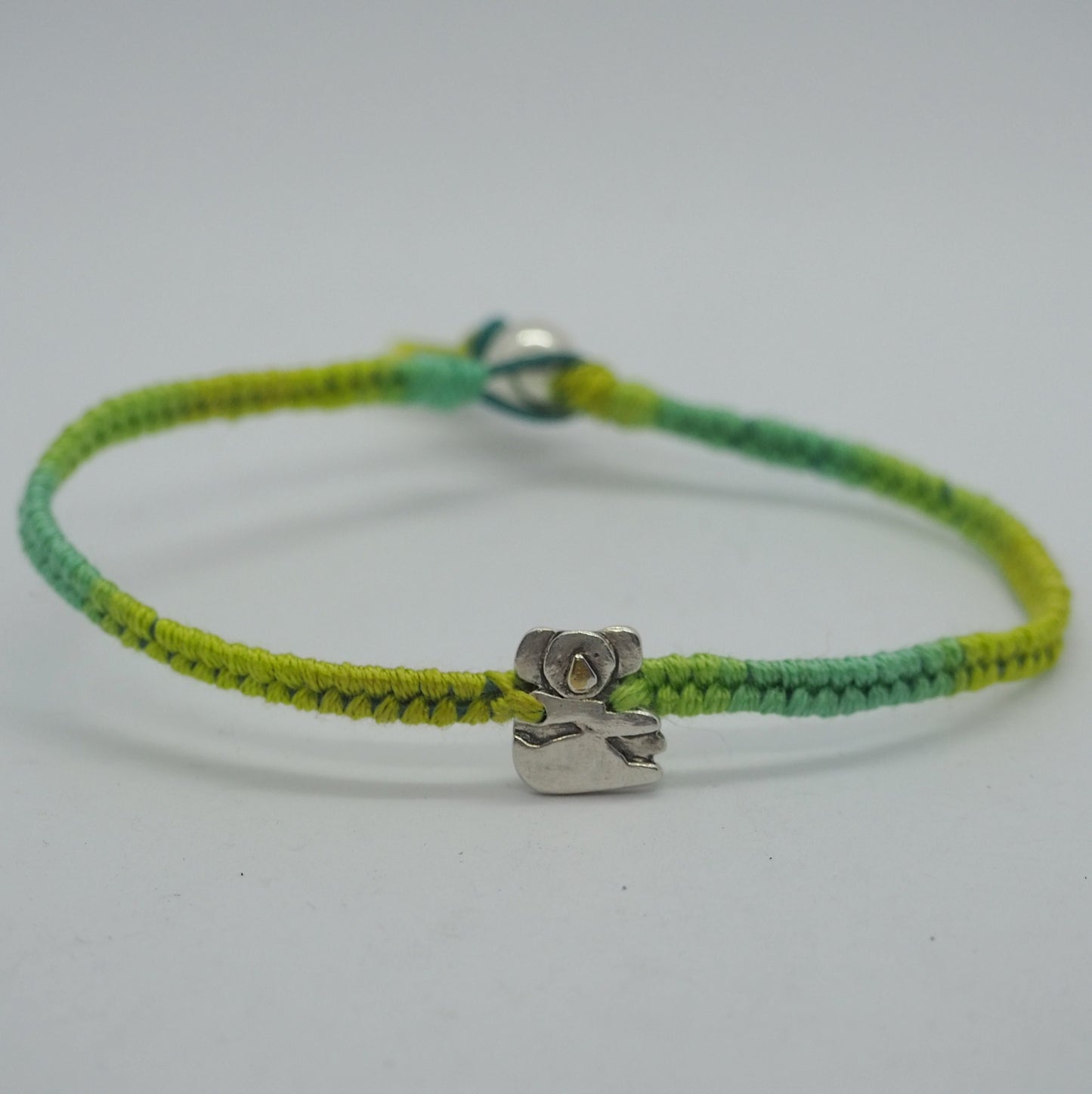 A gorgeous little fine silver koala with a golden nose on a beautiful greens leather, cotton and sterling silver friendship bracelet.