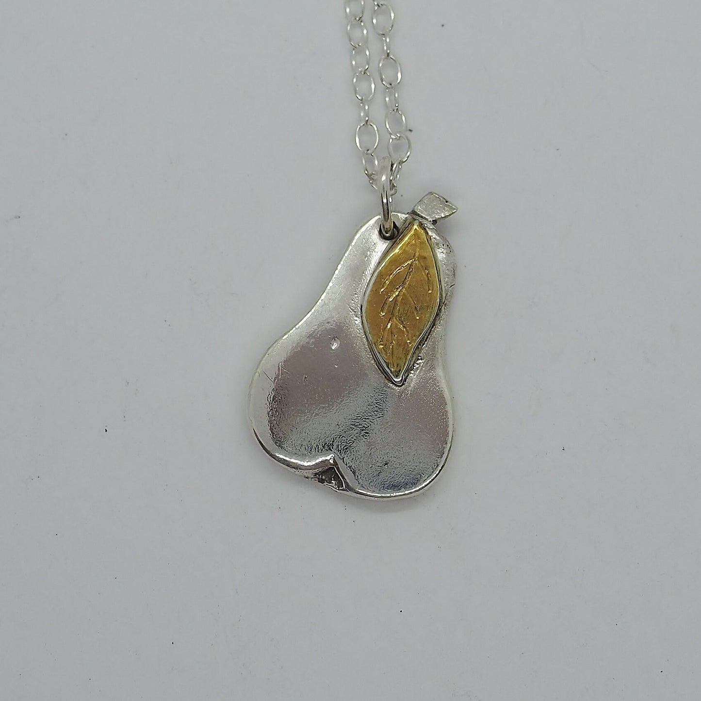 A gorgeous simple little pear hand made in eco friendly fine silver, with a 24k gold leaf on a sterling silver chain.