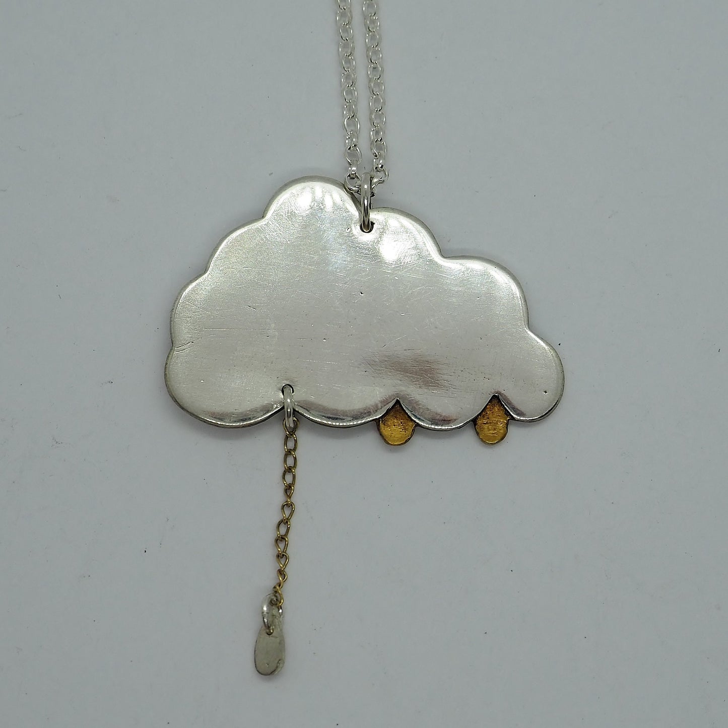 A simply adorable fine silver cloud pendant with tiny golden raindrops, one hung from 9ct gold chain hung on a sterling silver chain.