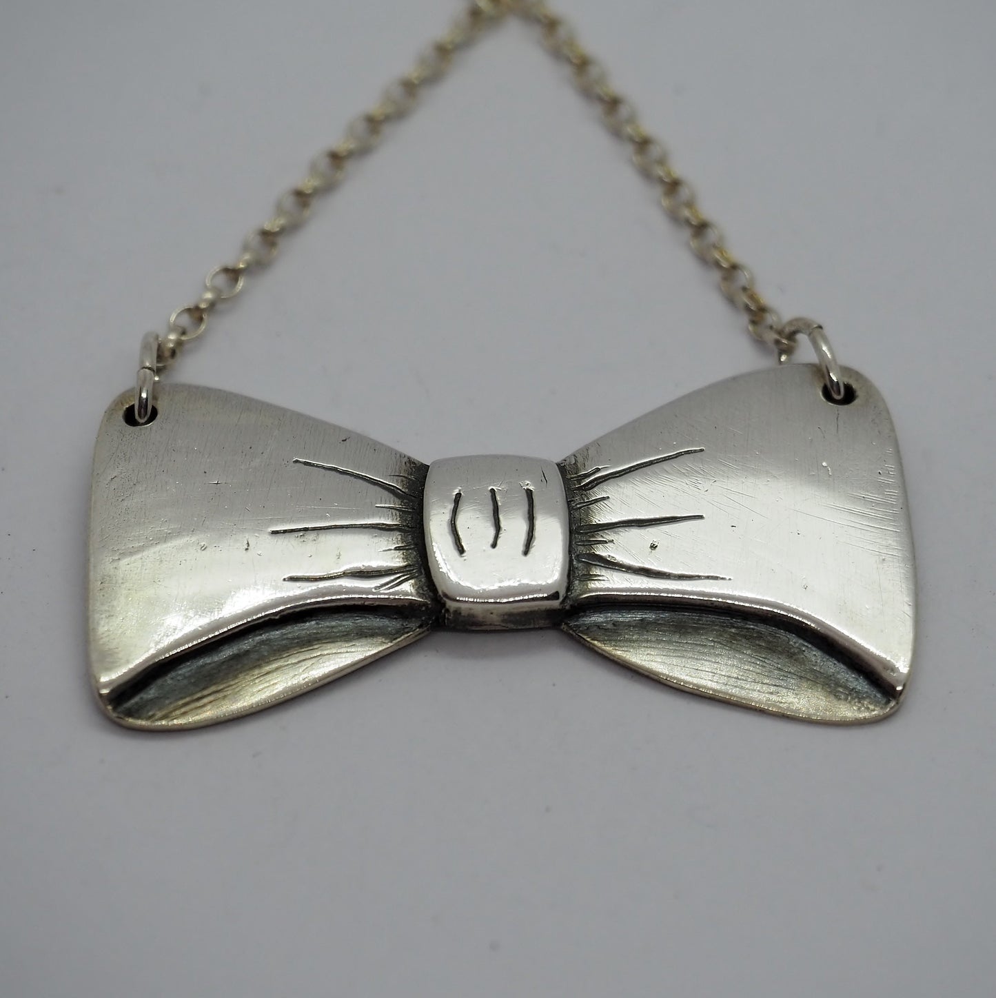 An adorable simple bow necklace handmade in fine silver on a sterling silver chain.