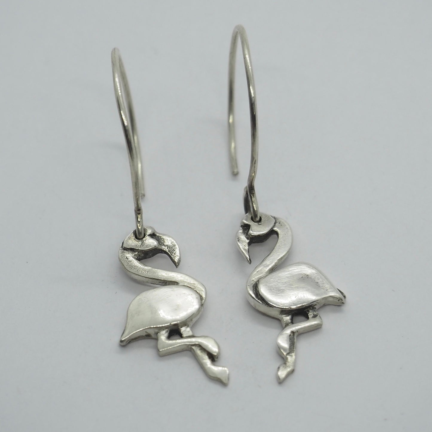 A gorgeous pair of handmade fine silver flamingo earrings hung on sterling silver wires.