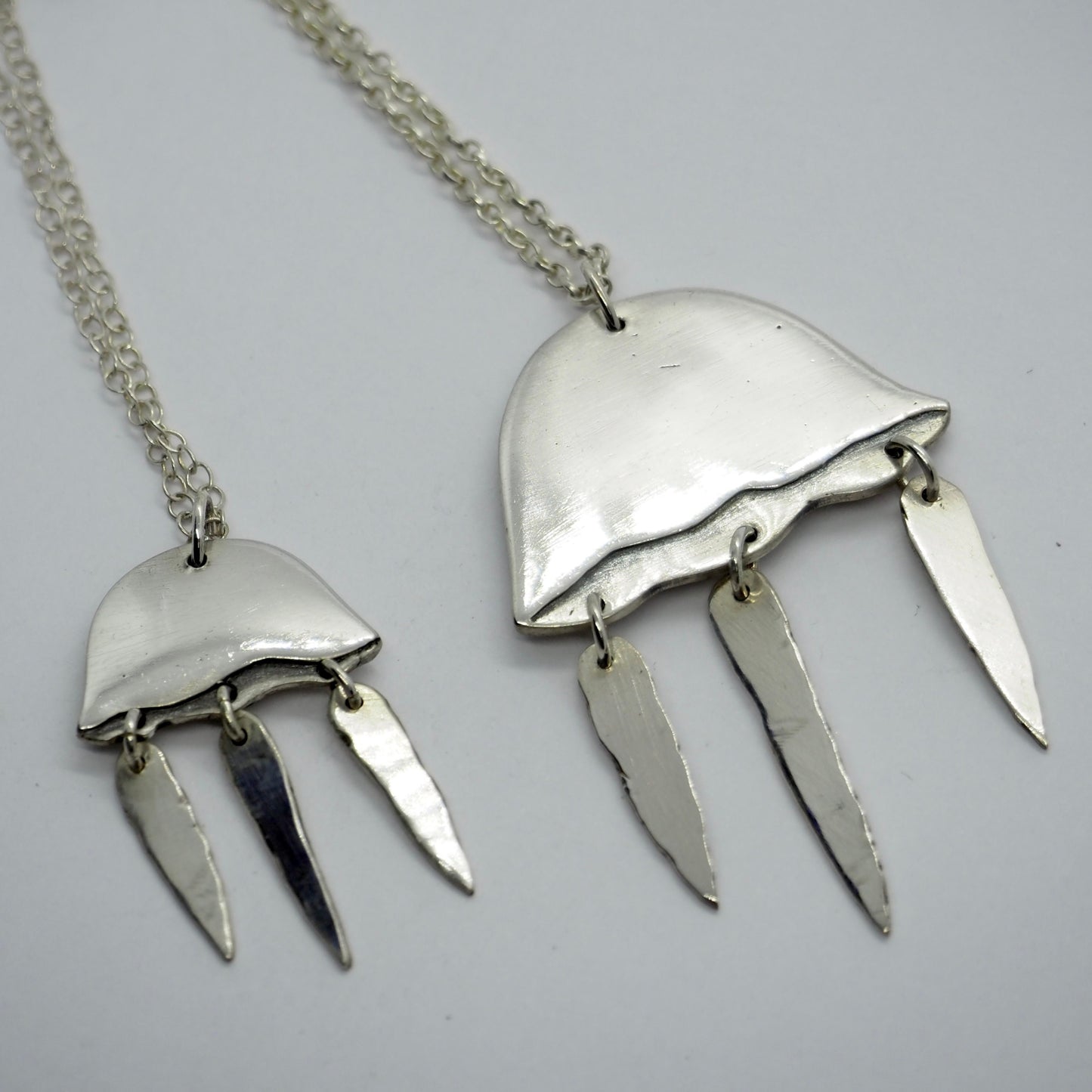 A gorgeous jellyfish pendant handmade in fine silver with hand cut sterling silver tentacles, hanging from a sterling chain.