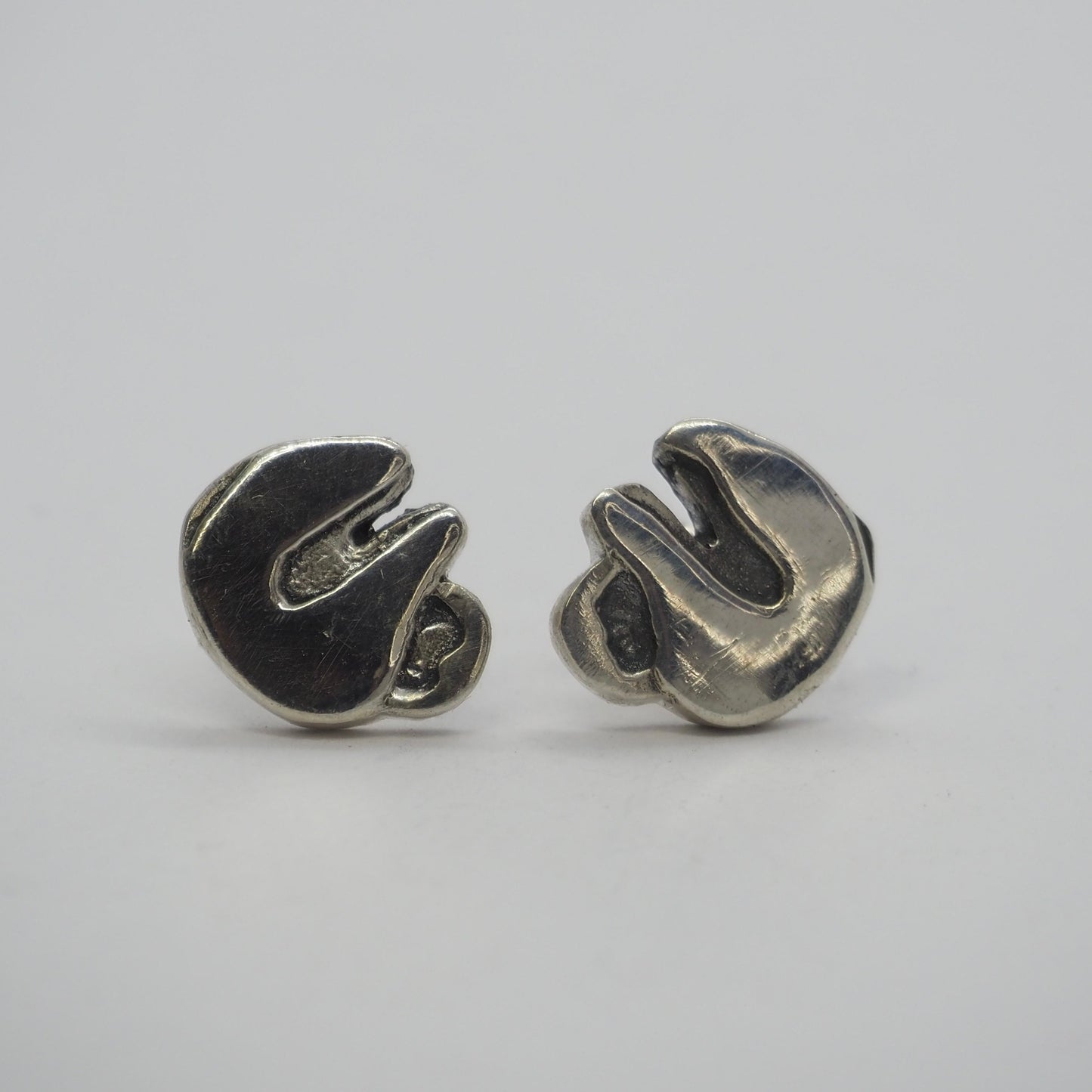 A gorgeous pair of tiny handmade fine silver sloth stud earrings on sterling silver posts.
