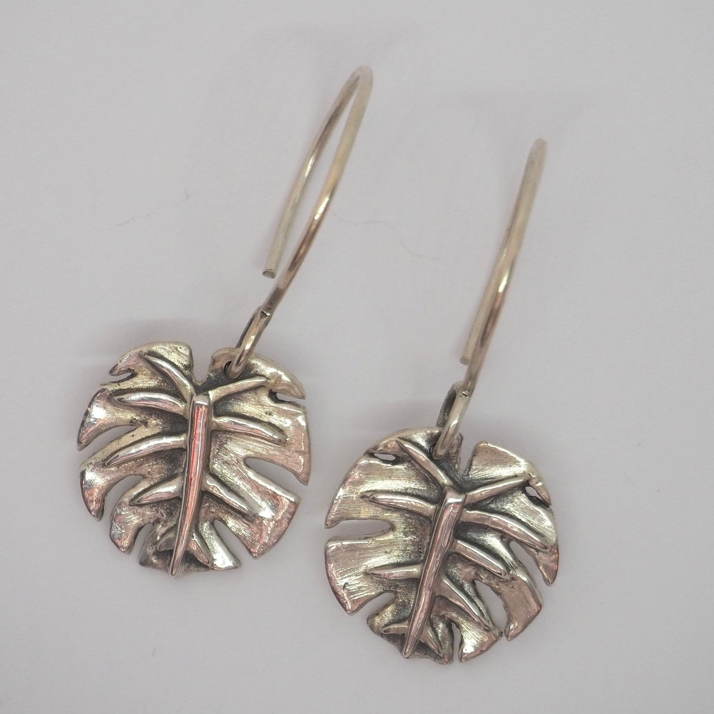 A beautiful pair of handmade eco friendly fine silver monstera leaf earrings on sterling silver wires.