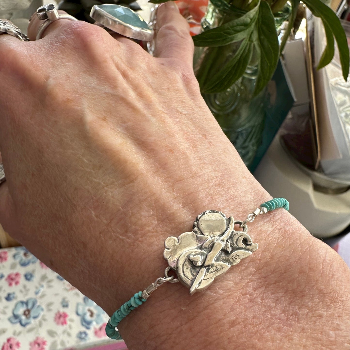 A beautiful handmade fine silver cold water sea swimmer charm strung on a bracelet of tiny turquoise and sterling silver beads.