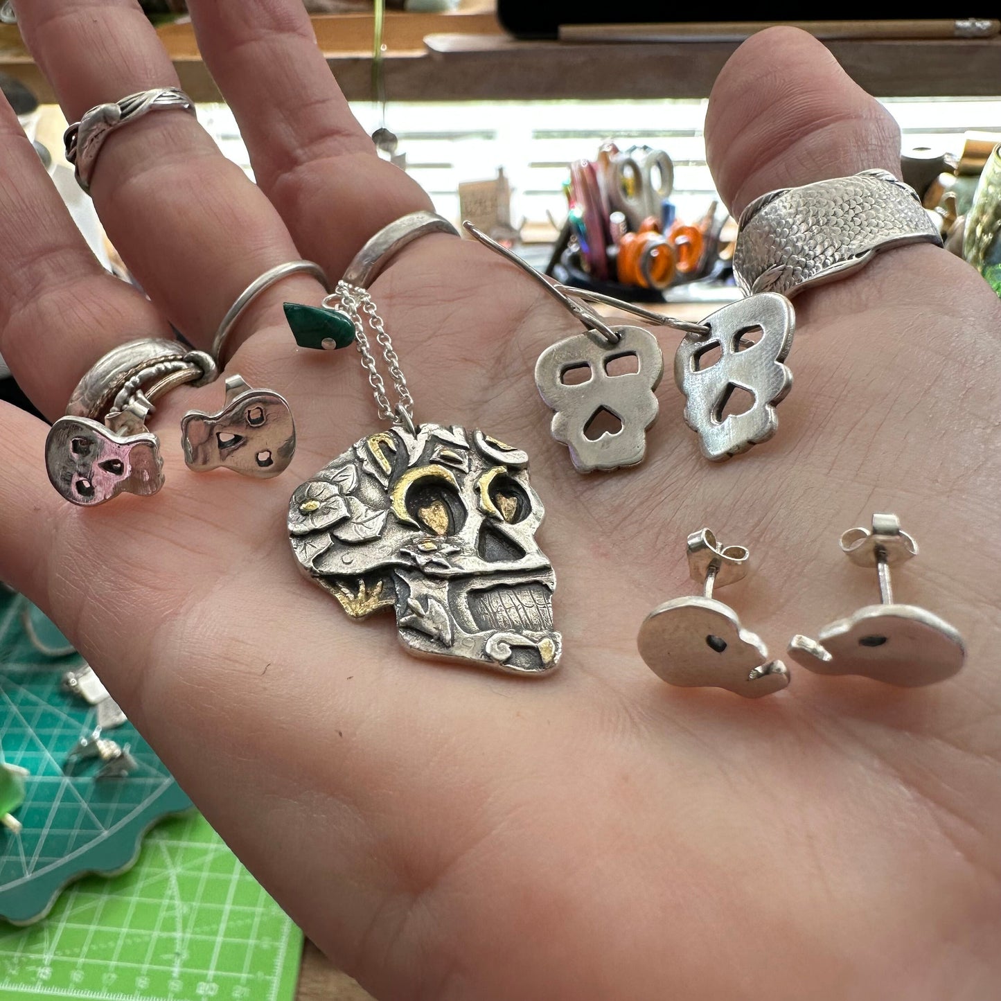 A gorgeous handmade, unique fine silver sugar skull pendant with a gold details hanging on a sterling silver chain.