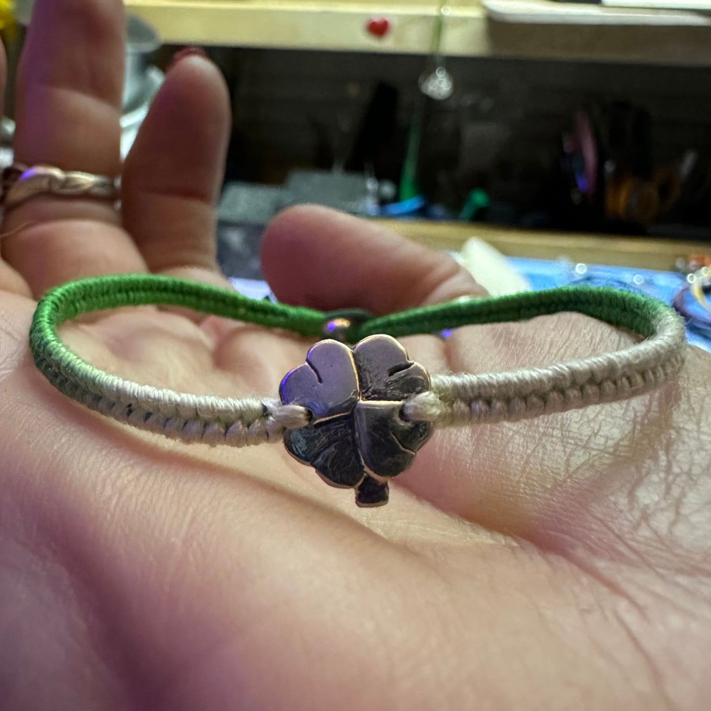 A beautiful green leather, cotton and sterling silver friendship bracelet with a fine silver shamrock four leaf clover.
