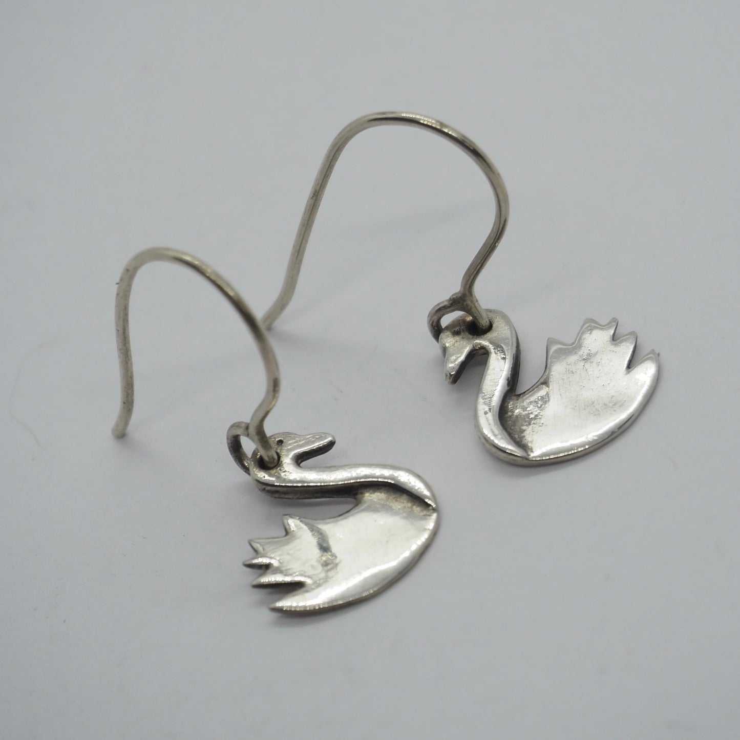 A simple pair of swan earrings in handmade in fine silver hung on sterling silver wires.