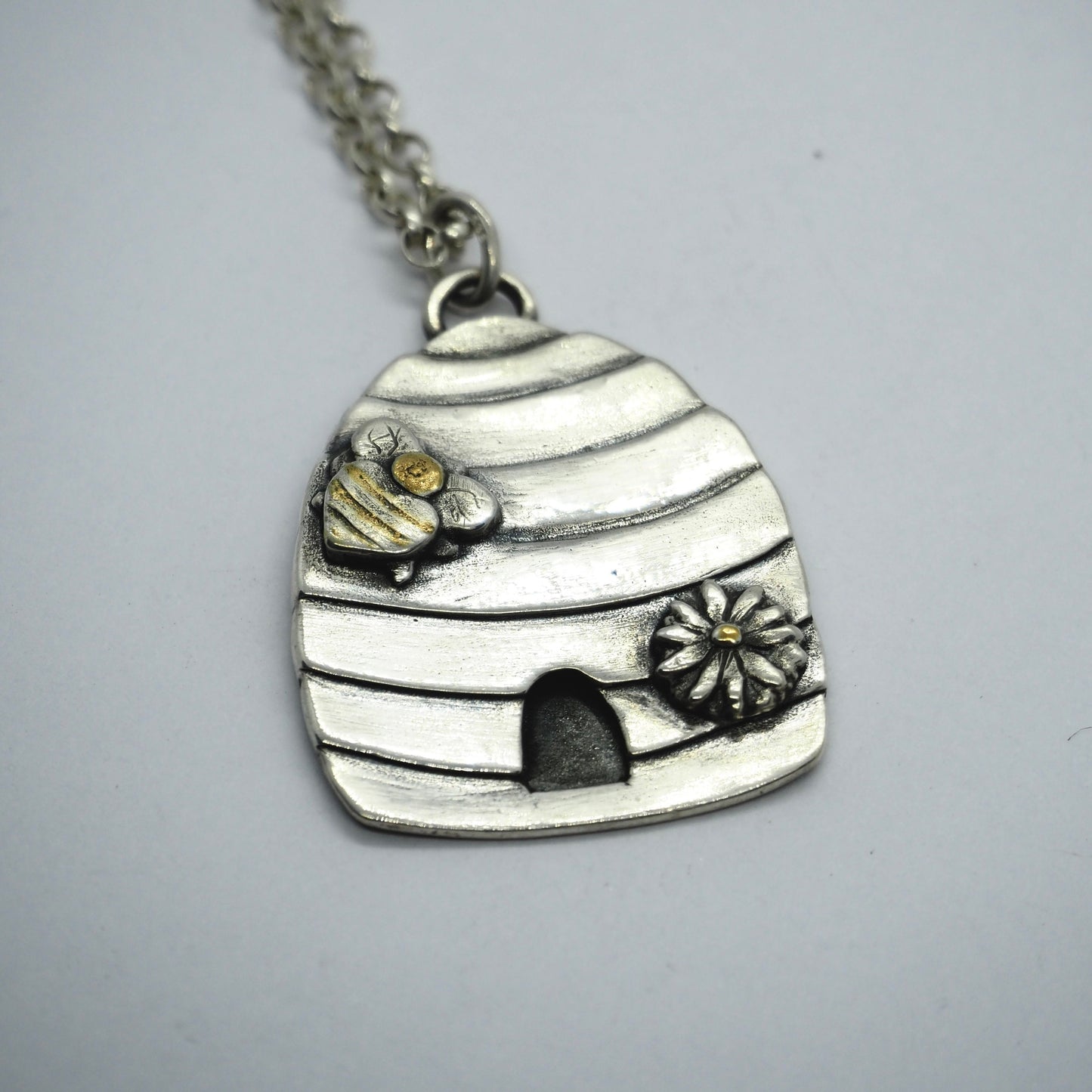 A beautiful fine silver beehive pendant on a sterling silver chain with a 24k gold highlights…