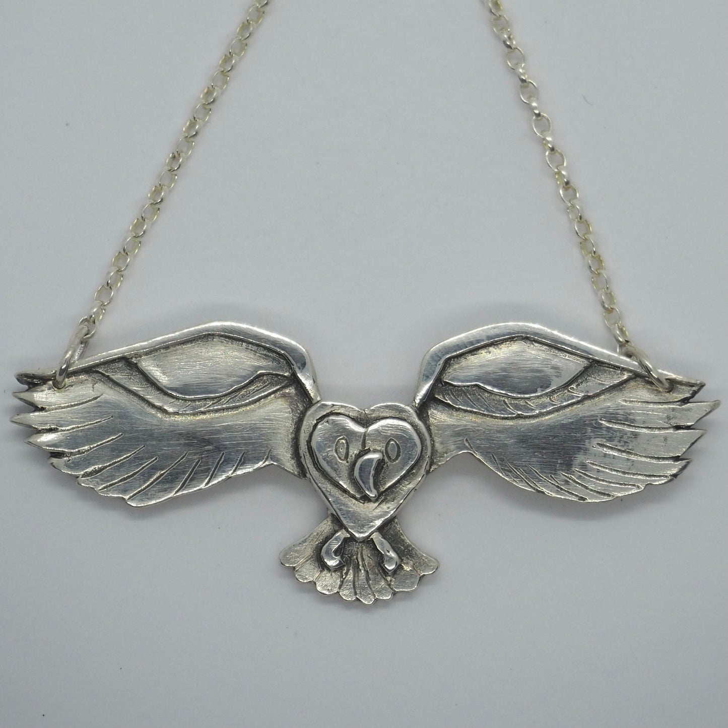 A beautiful simple flying great grey owl necklace handmade in fine silver hung on a sterling silver chain.