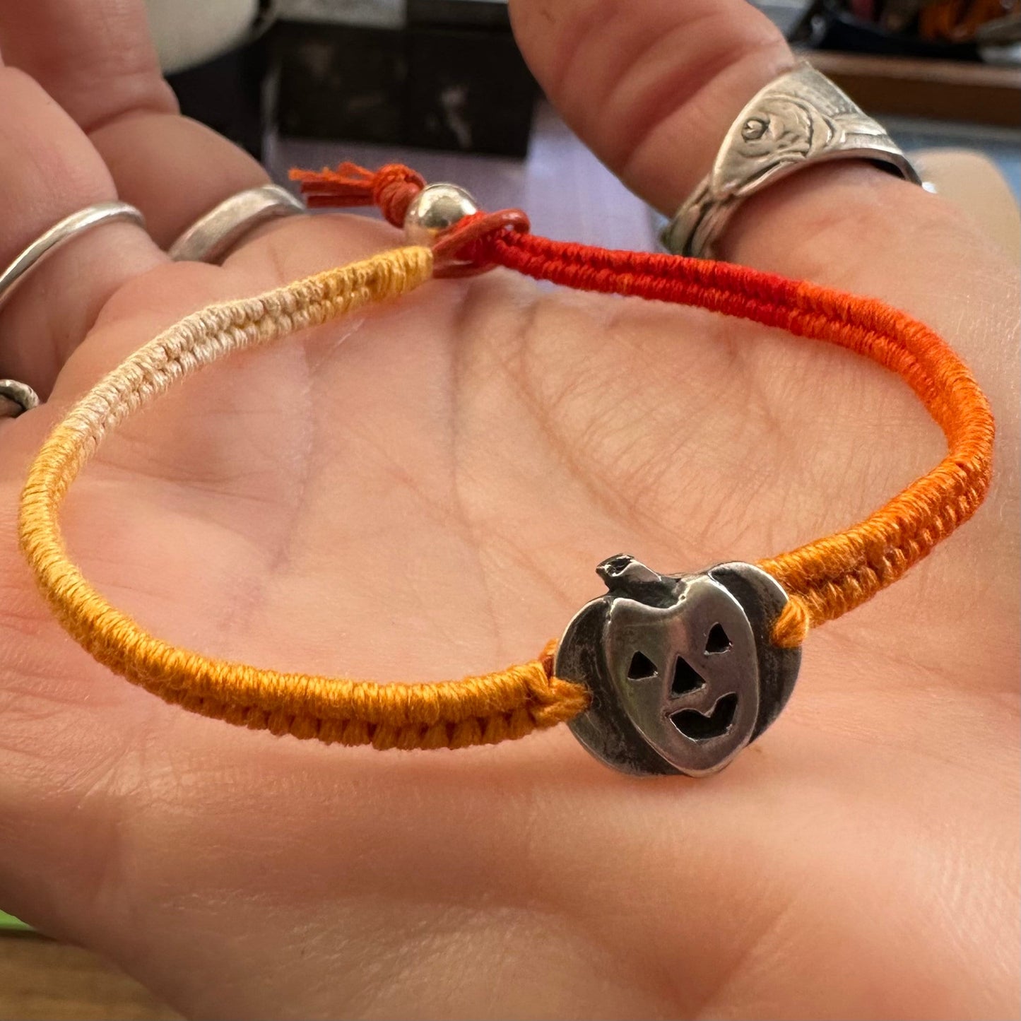 A unique tiny fine silver pumpkin jack o lantern on a beautiful orange leather, sterling silver and cotton friendship bracelet.