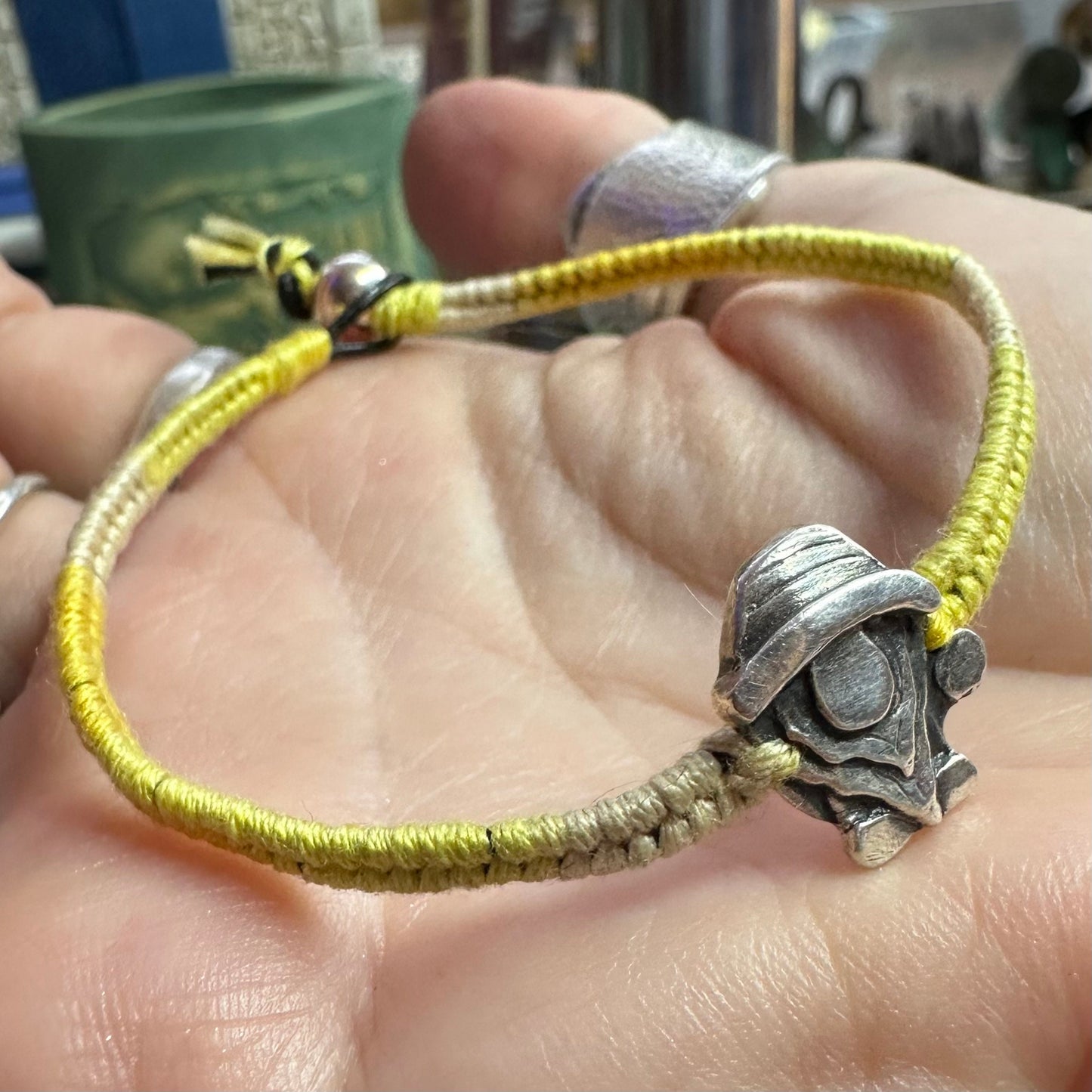 A handmade fine silver Norm nisse gnome on a lovely yellow leather and cotton friendship bracelet, finished with a sterling silver bead.