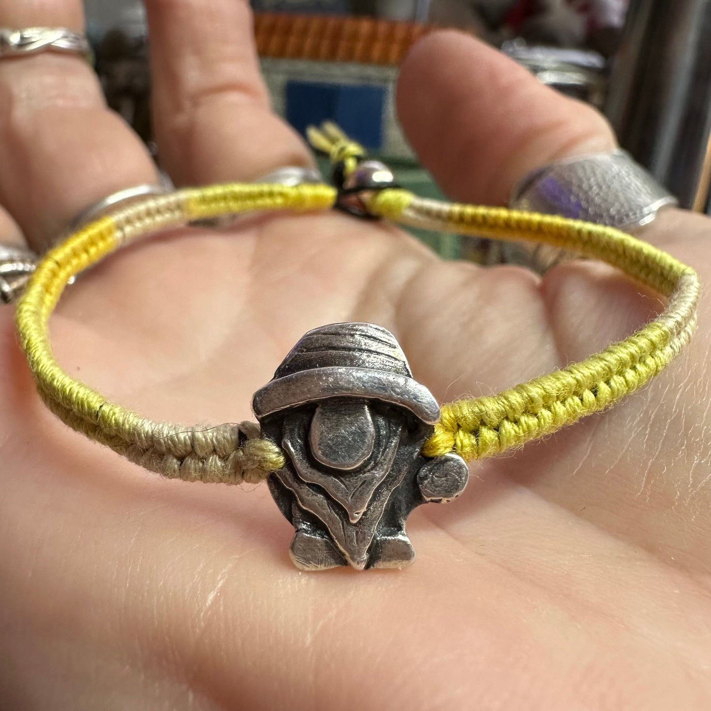 A handmade fine silver Norm nisse gnome on a lovely yellow leather and cotton friendship bracelet, finished with a sterling silver bead.