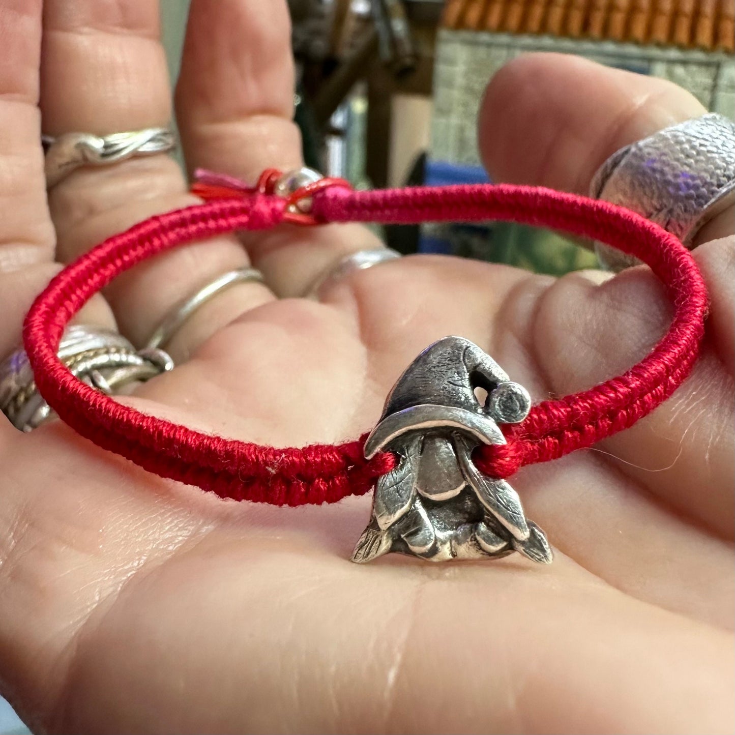A handmade fine silver Norma nisse lady gnome on a fab red leather and cotton friendship bracelet, finished with a sterling silver bead.