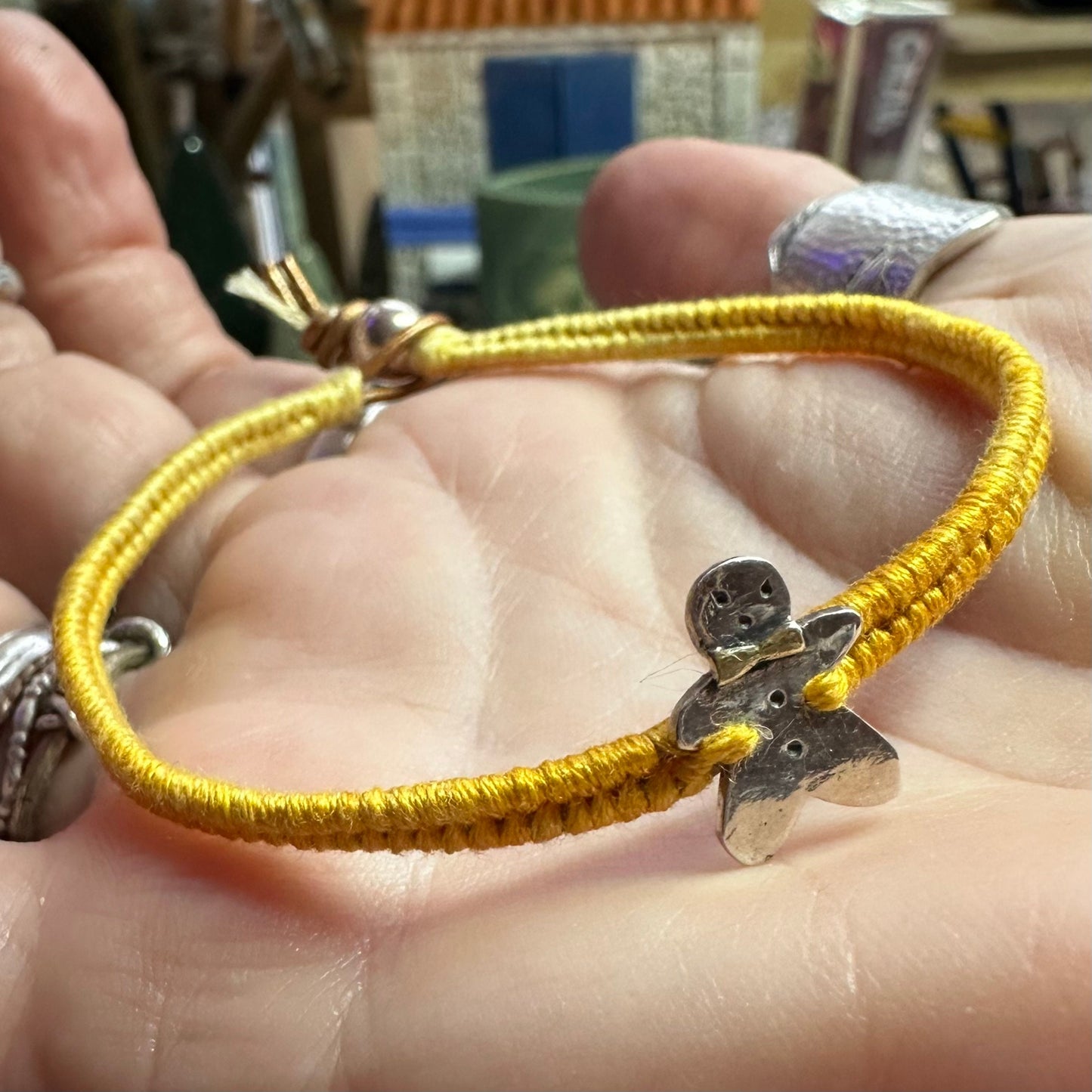 A handmade fine silver gingerbread man with a gold bow tie on a lovely yellow leather, cotton and sterling silver woven friendship bracelet…