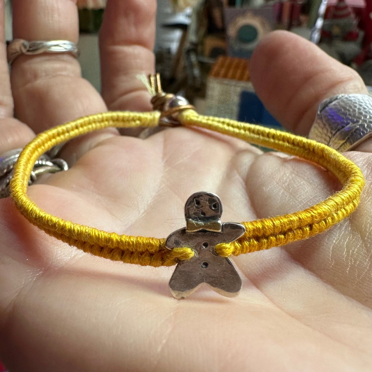 A handmade fine silver gingerbread man with a gold bow tie on a lovely yellow leather, cotton and sterling silver woven friendship bracelet…