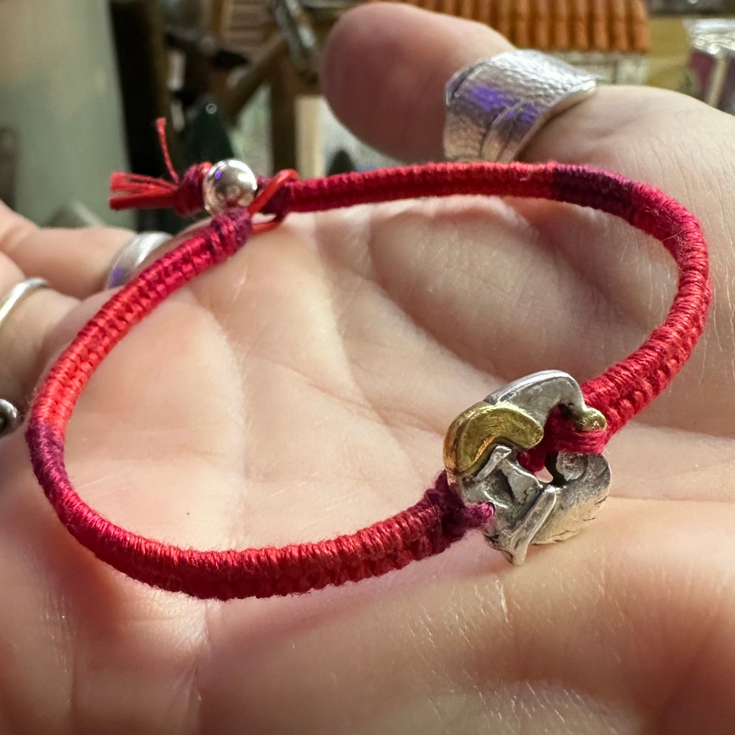 An adorable handmade fine silver Santa with gold trim on a vivid red leather, cotton and sterling silver woven friendship bracelet…