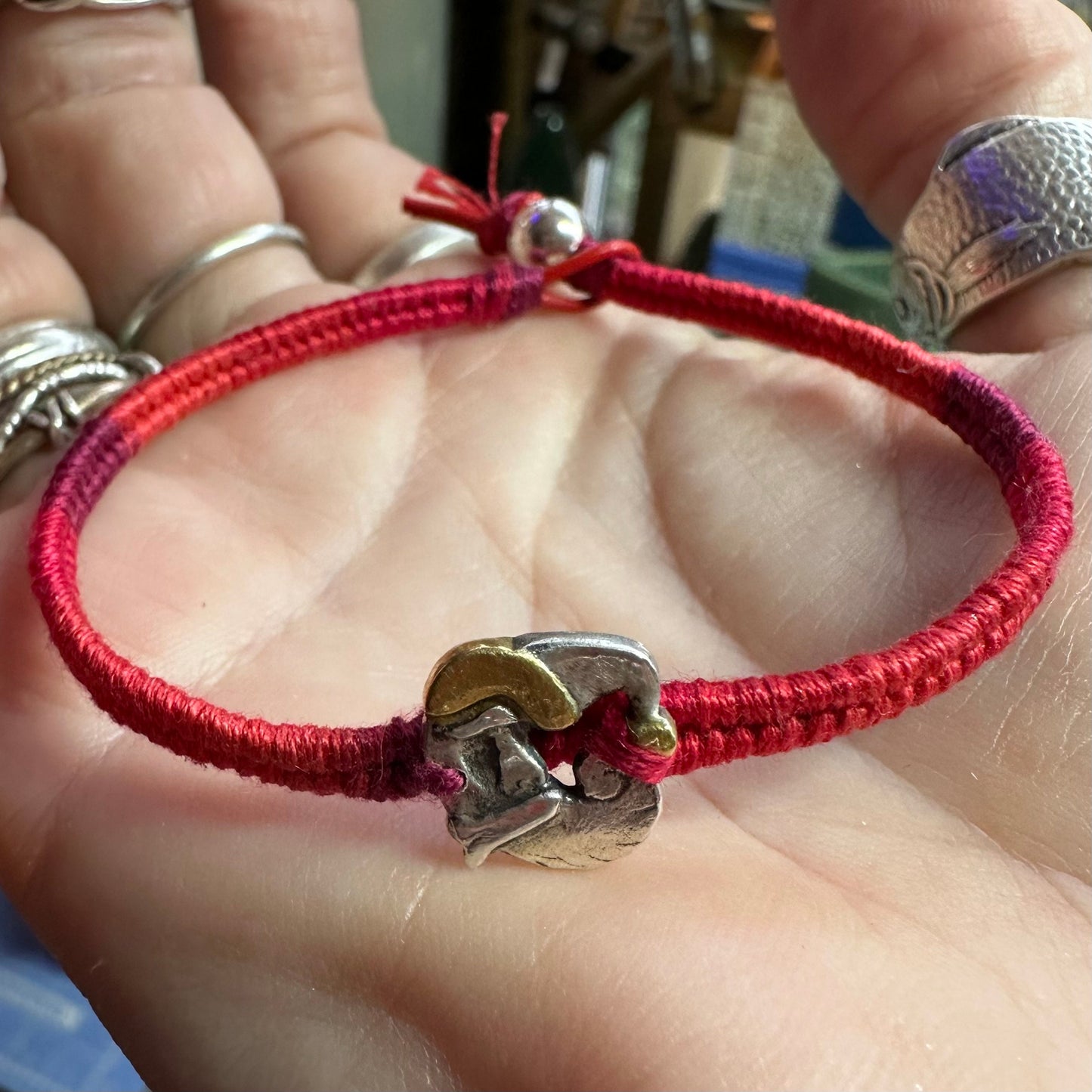 An adorable handmade fine silver Santa with gold trim on a vivid red leather, cotton and sterling silver woven friendship bracelet…