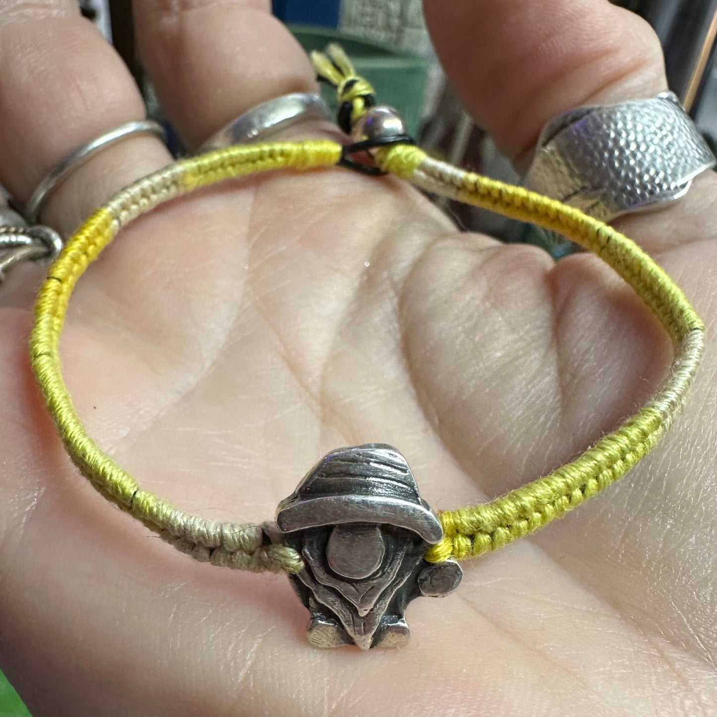 A handmade fine silver Norm nisse gnome on a lovely yellow leather and cotton friendship bracelet, finished with a sterling silver bead.
