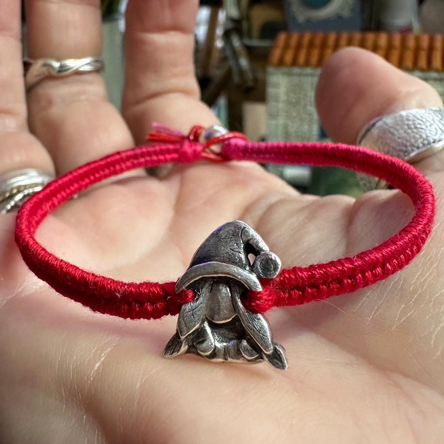 A handmade fine silver Norma nisse lady gnome on a fab red leather and cotton friendship bracelet, finished with a sterling silver bead.