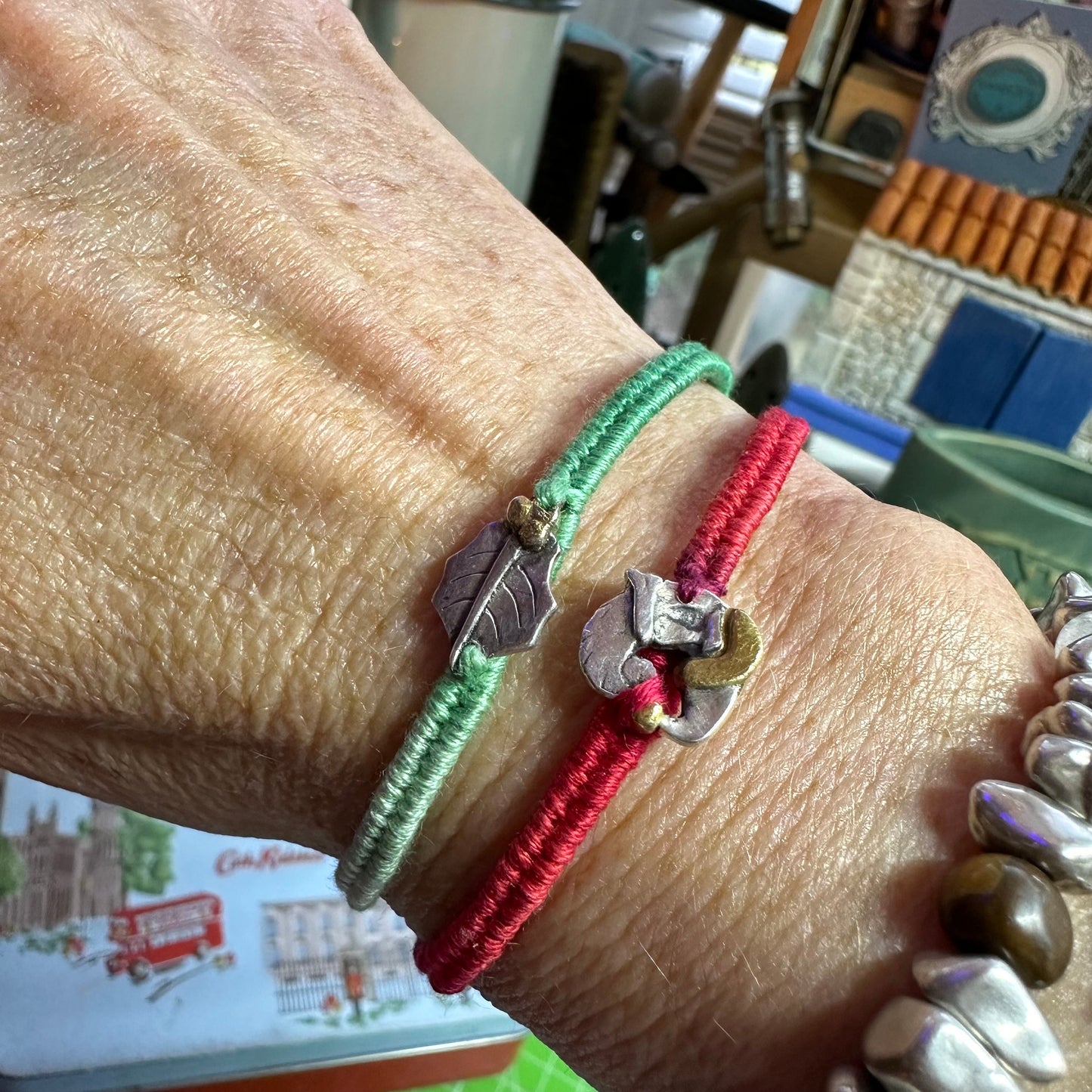 A delightful handmade fine silver wreath with gold decorations on a green leather, cotton and sterling silver woven friendship bracelet