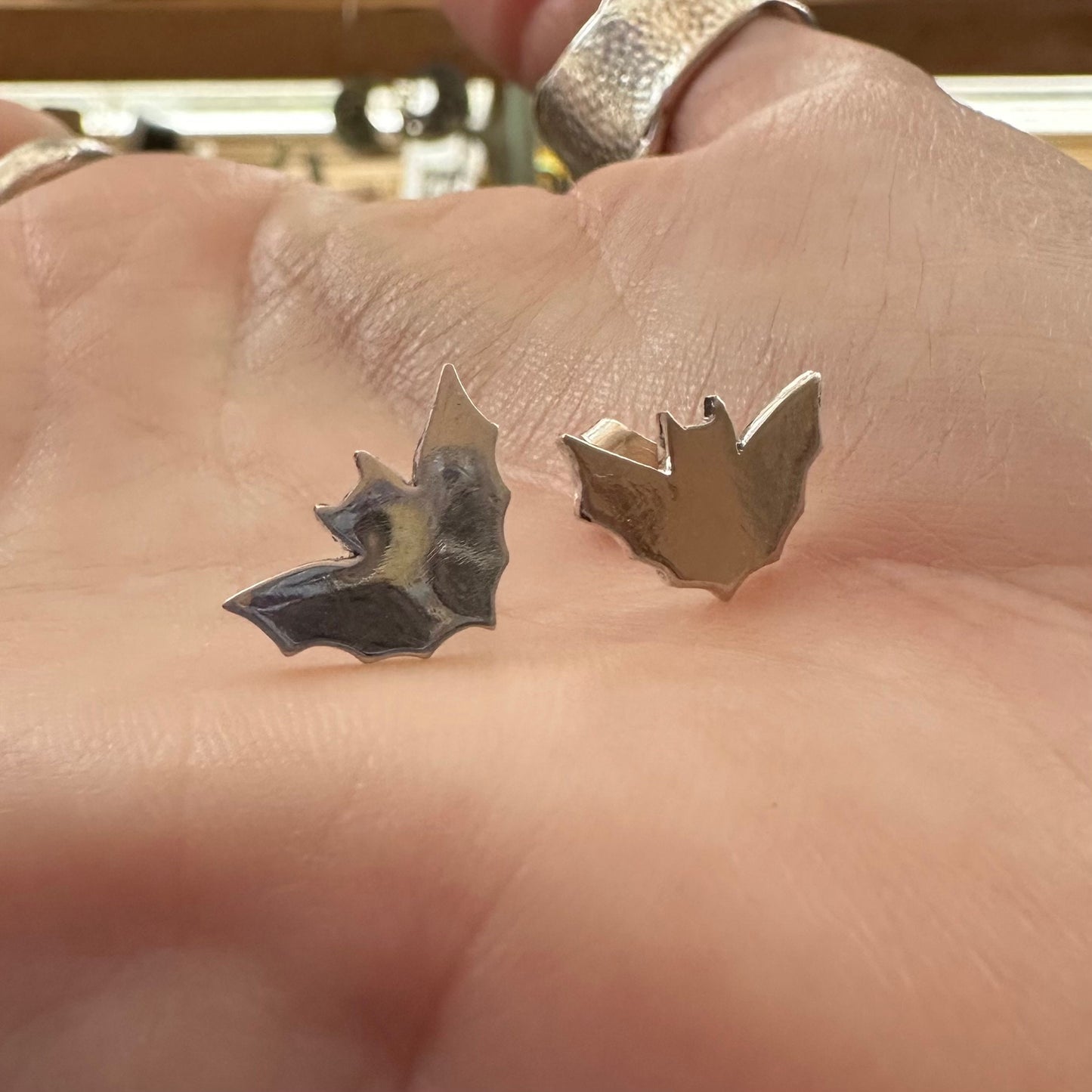 A pair of little fine silver bat stud earrings on sterling silver posts.