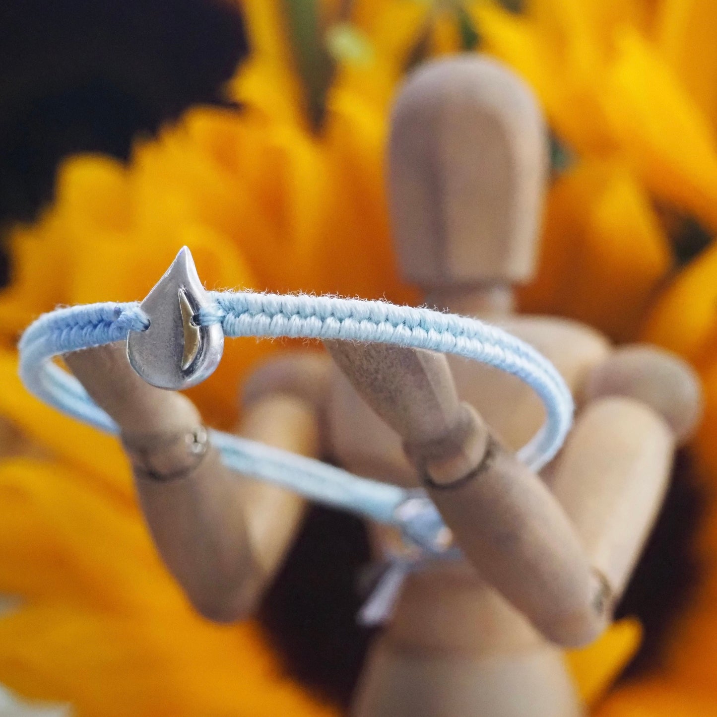 A gorgeous simple fine silver raindrop with gold highlights on a lovely blue leather, cotton and sterling silver friendship bracelet.