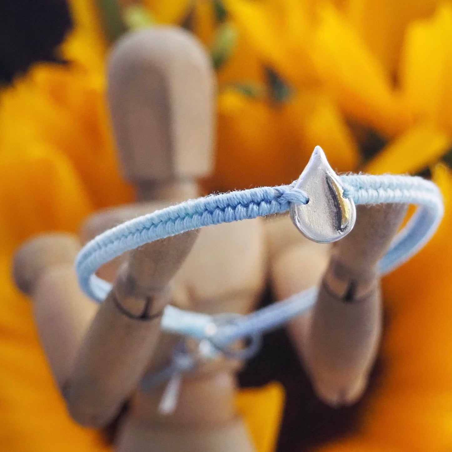 A gorgeous simple fine silver raindrop with gold highlights on a lovely blue leather, cotton and sterling silver friendship bracelet.