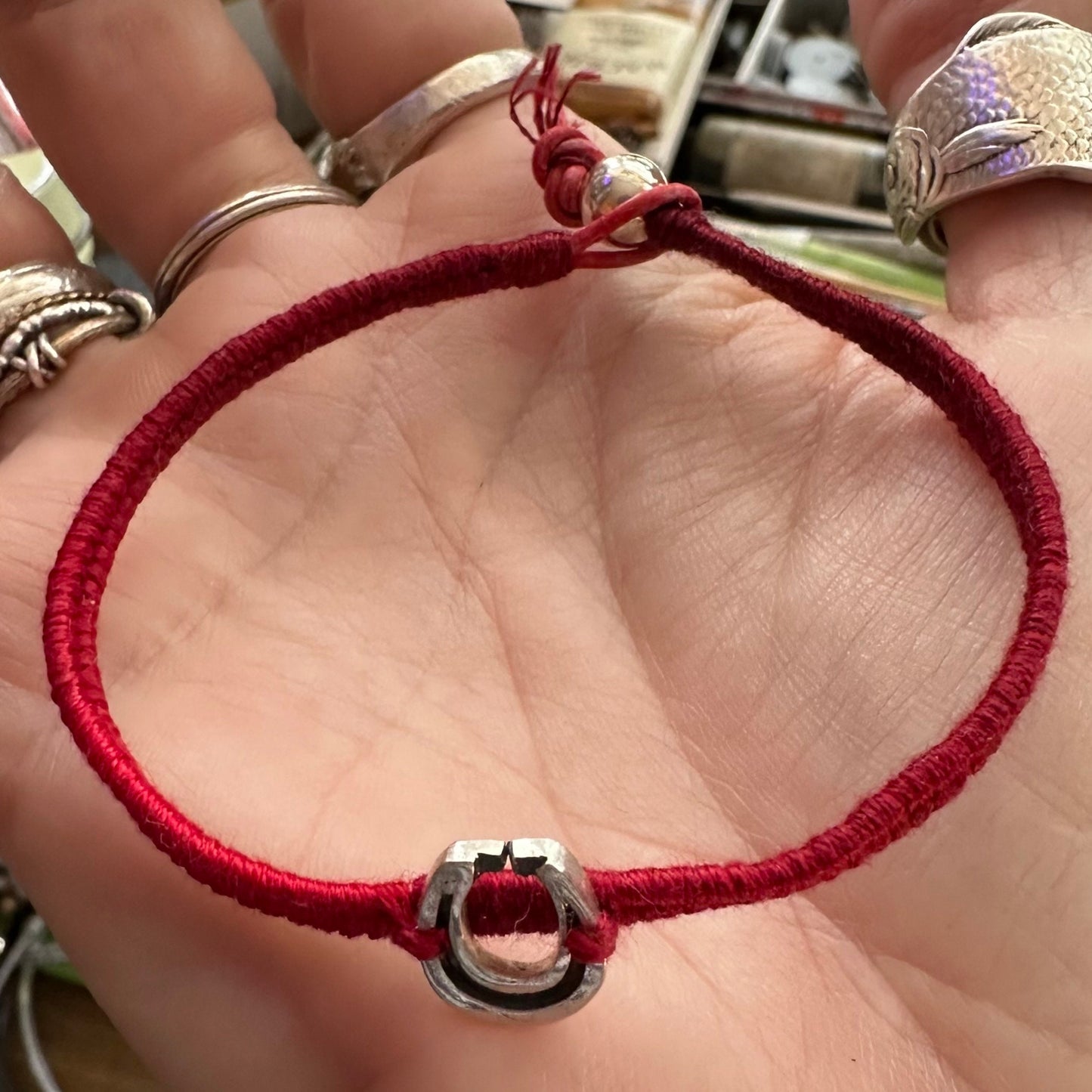 A gorgeous simple handmade fine silver horseshoe on a deep reds leather, sterling silver and cotton friendship bracelet.