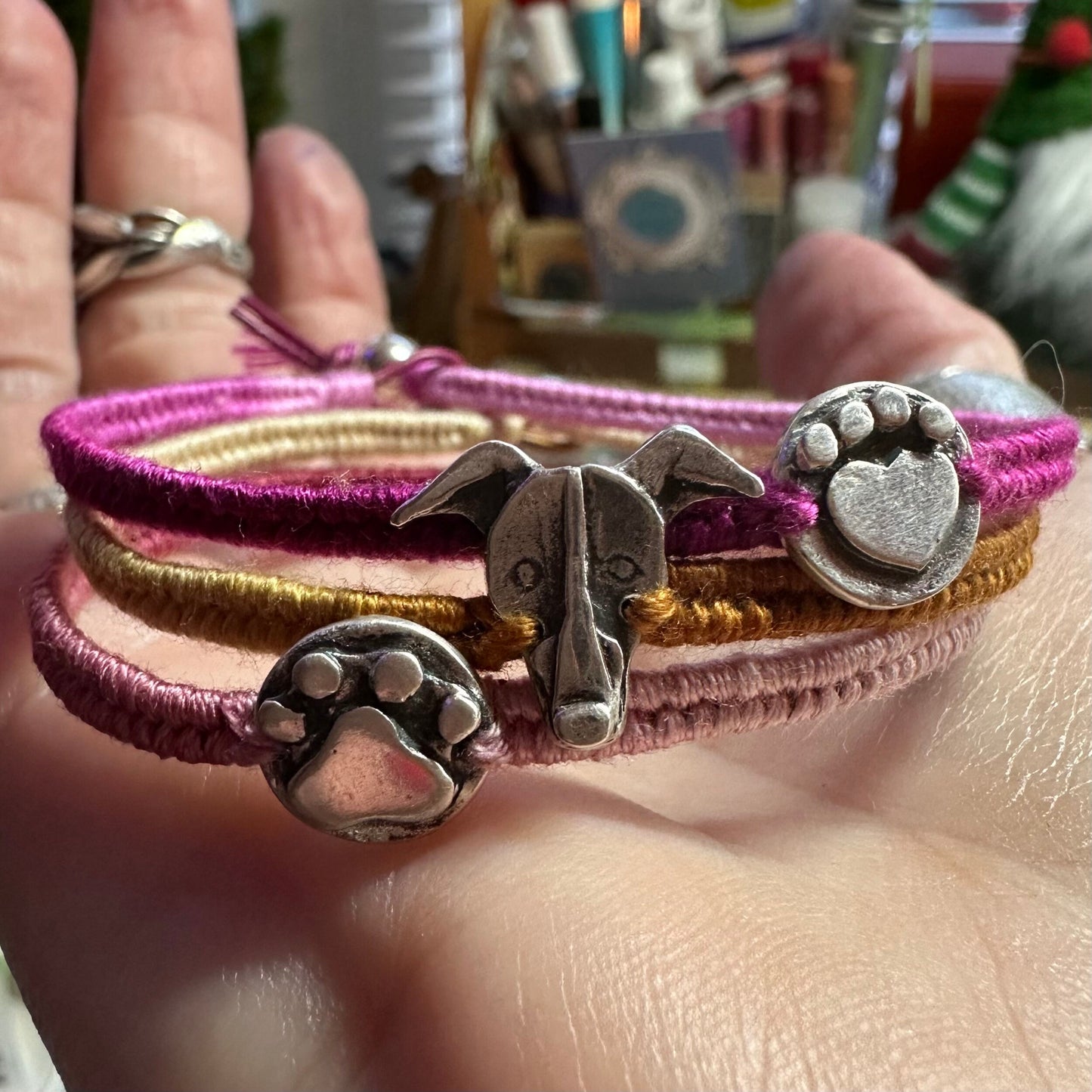 An adorable handmade fine silver heart paw print on a beautiful soft pink leather and cotton friendship bracelet.
