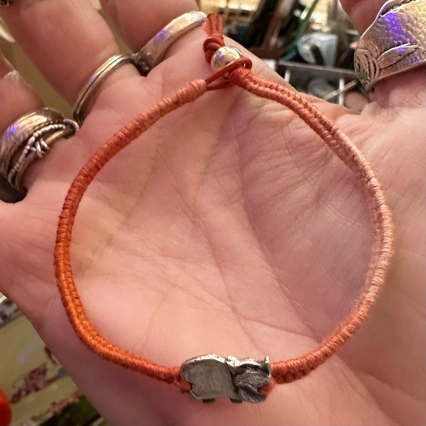 A cute little handmade fine silver highland cow on a vivid browny/orange leather, cotton and sterling silver woven friendship bracelet…