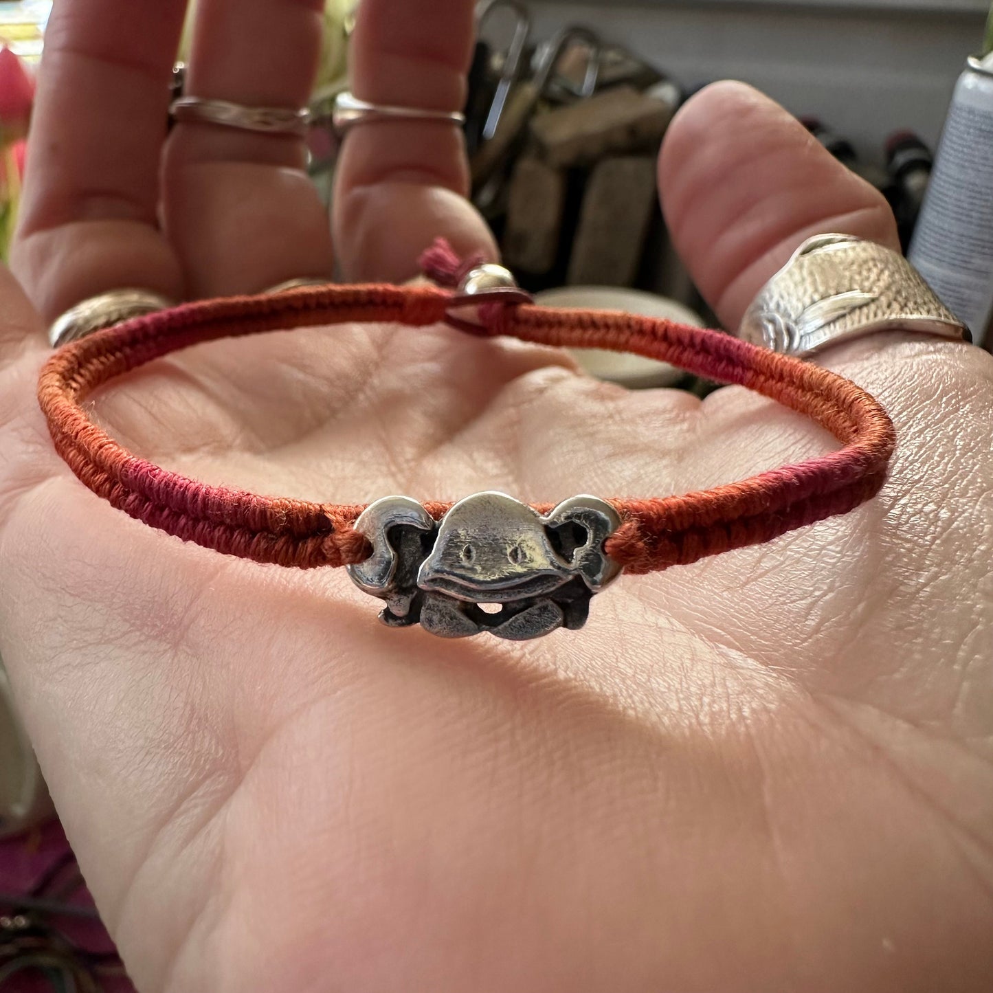 A cute handmade fine silver crab on a vivid red and orange leather, cotton and sterling silver woven friendship bracelet…