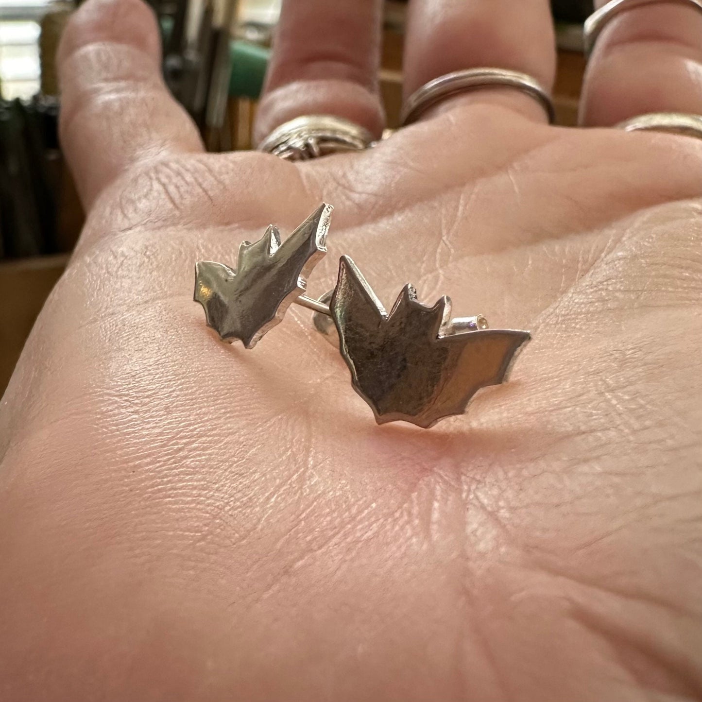 A pair of little fine silver bat stud earrings on sterling silver posts.